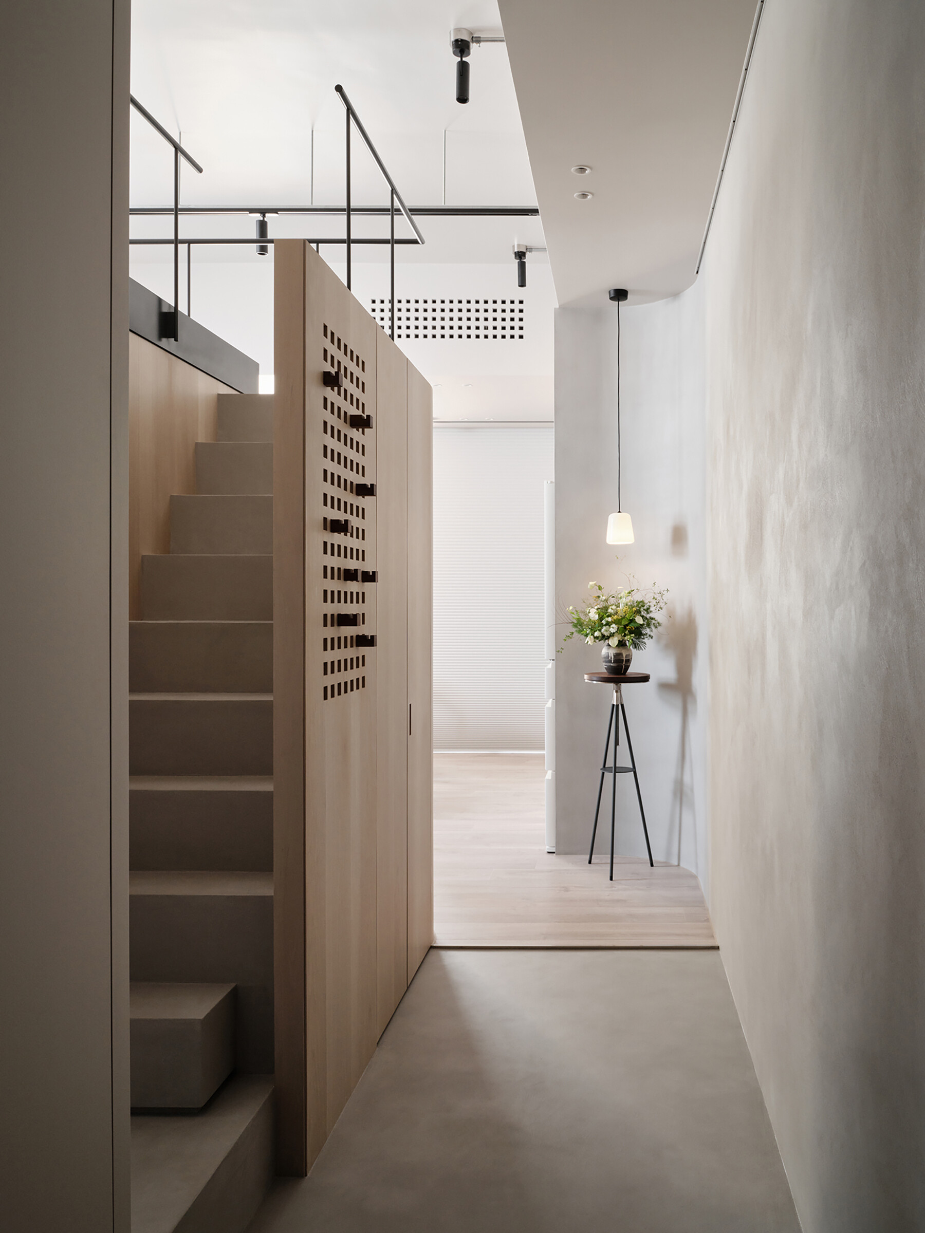 This staircase leading to the loft is more than just a means of access, it’s an architectural feature. Rather than feeling bulky, it reads as an extension of the home’s material language. Slim, pale wood treads and light metal framing keep the look airy, while maintaining stability and safety. The stair’s placement also supports the apartment’s “dual circulation” layout, ensuring clear, logical flow between living zones.