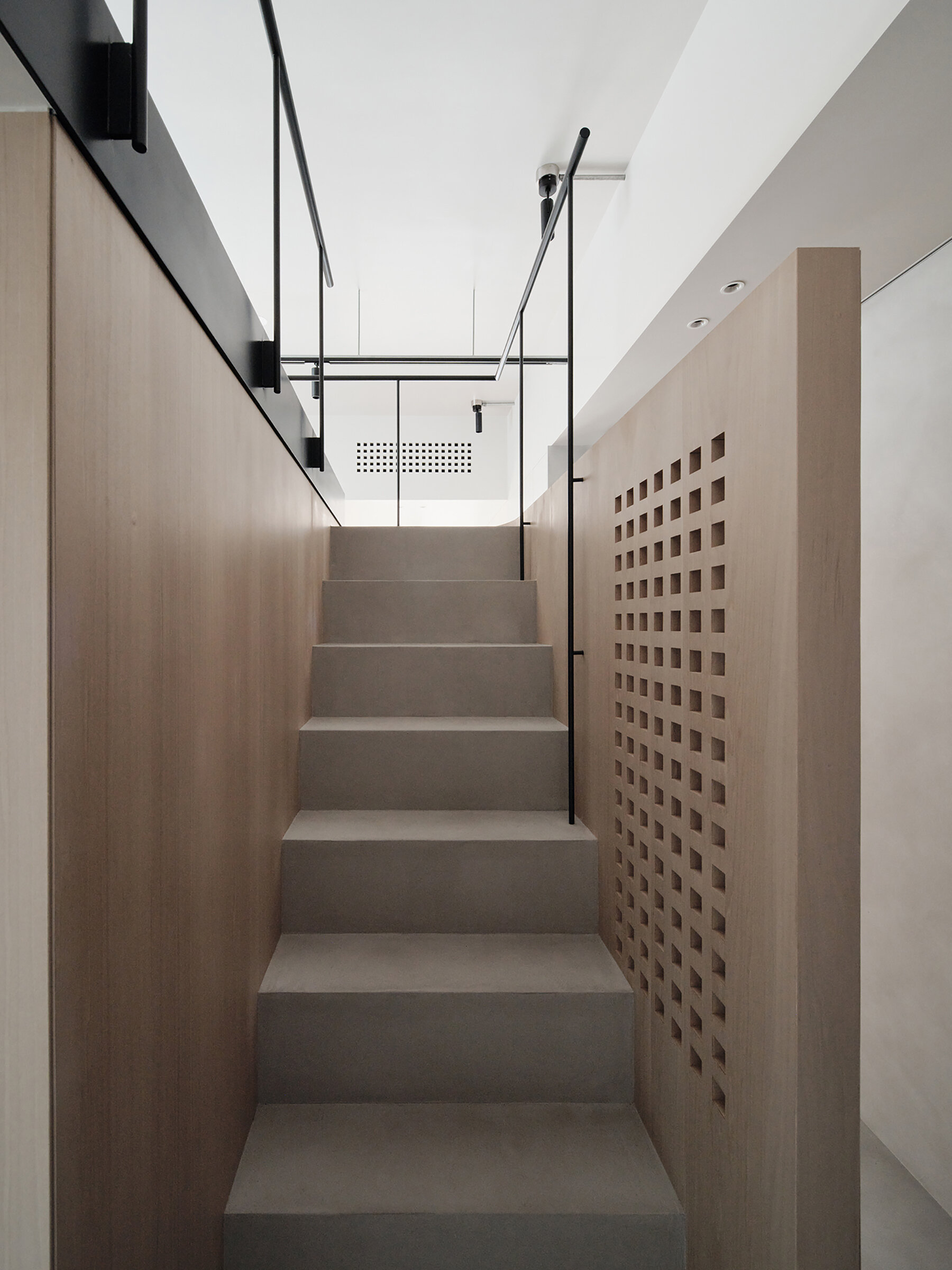 This staircase leading to the loft is more than just a means of access, it’s an architectural feature. Rather than feeling bulky, it reads as an extension of the home’s material language. Slim, pale wood treads and light metal framing keep the look airy, while maintaining stability and safety. The stair’s placement also supports the apartment’s “dual circulation” layout, ensuring clear, logical flow between living zones.
