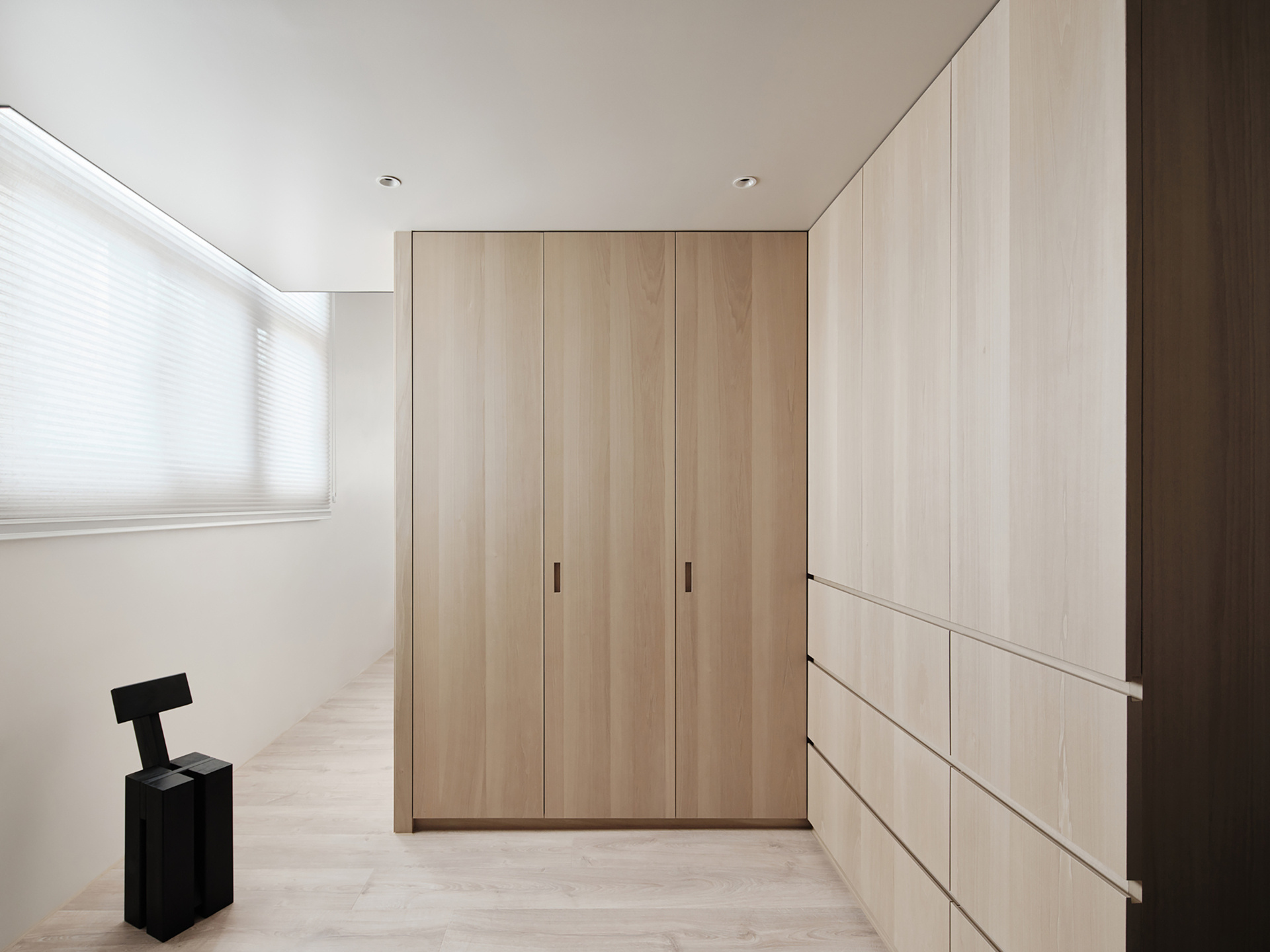 A dedicated wall underneath the loft bed houses everything from a wardrobe to a shoe cabinet, all tucked discreetly behind flush panels. This "storage core" keeps clutter completely out of sight, helping the living space breathe.