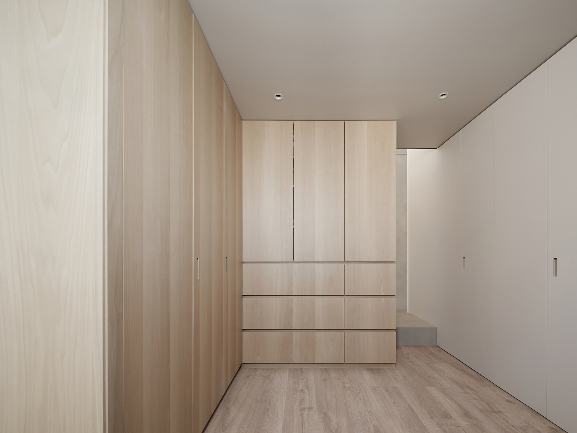 A dedicated wall underneath the loft bed houses everything from a wardrobe to a shoe cabinet, all tucked discreetly behind flush panels. This "storage core" keeps clutter completely out of sight, helping the living space breathe.