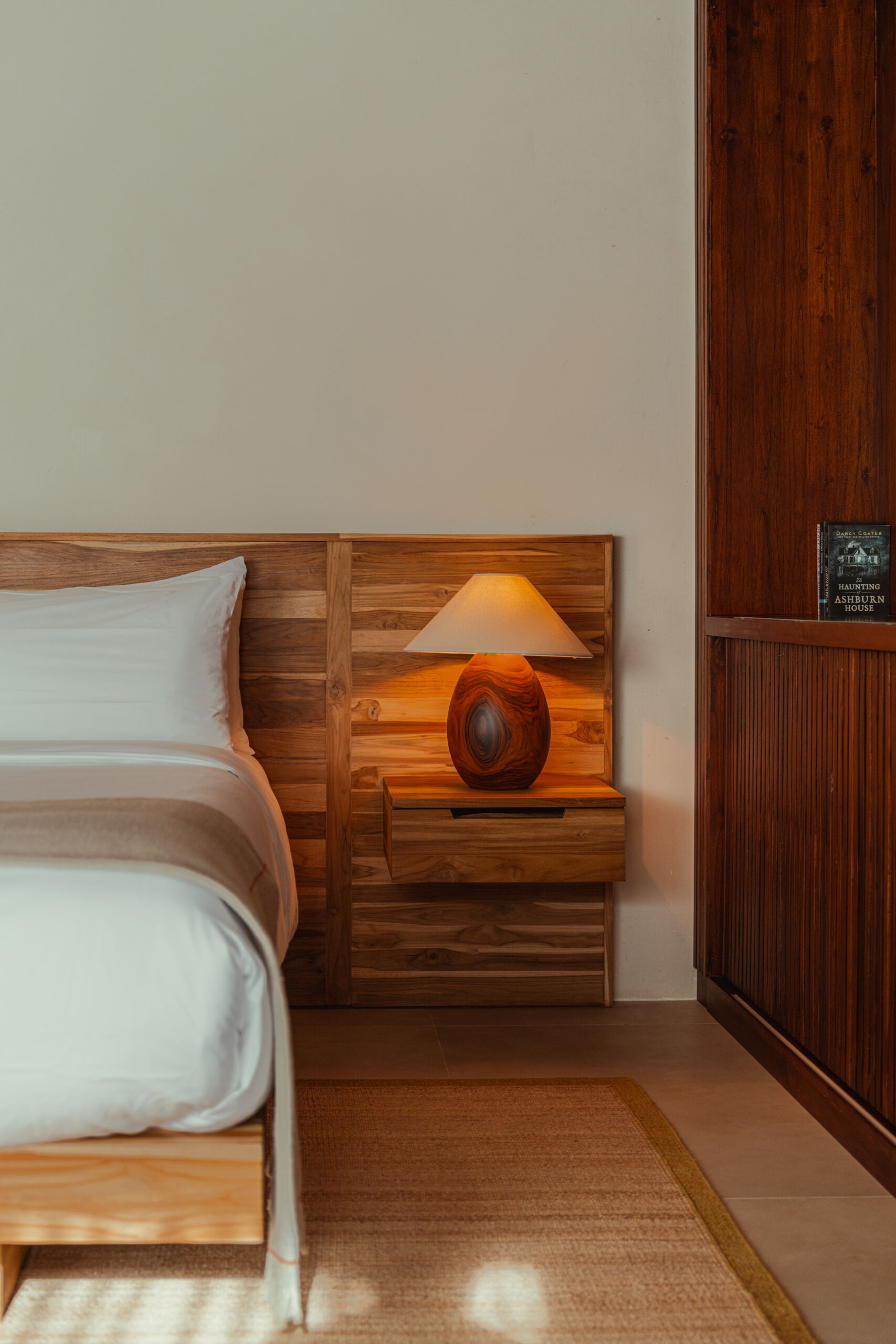 This warm, light-filled guest accommodation invites rest and relaxation. Sheer curtains, natural wood paneling and ceiling, and sculpted side tables create a calm, handcrafted feel, while the low bed and open layout make space for slow, restful moments.