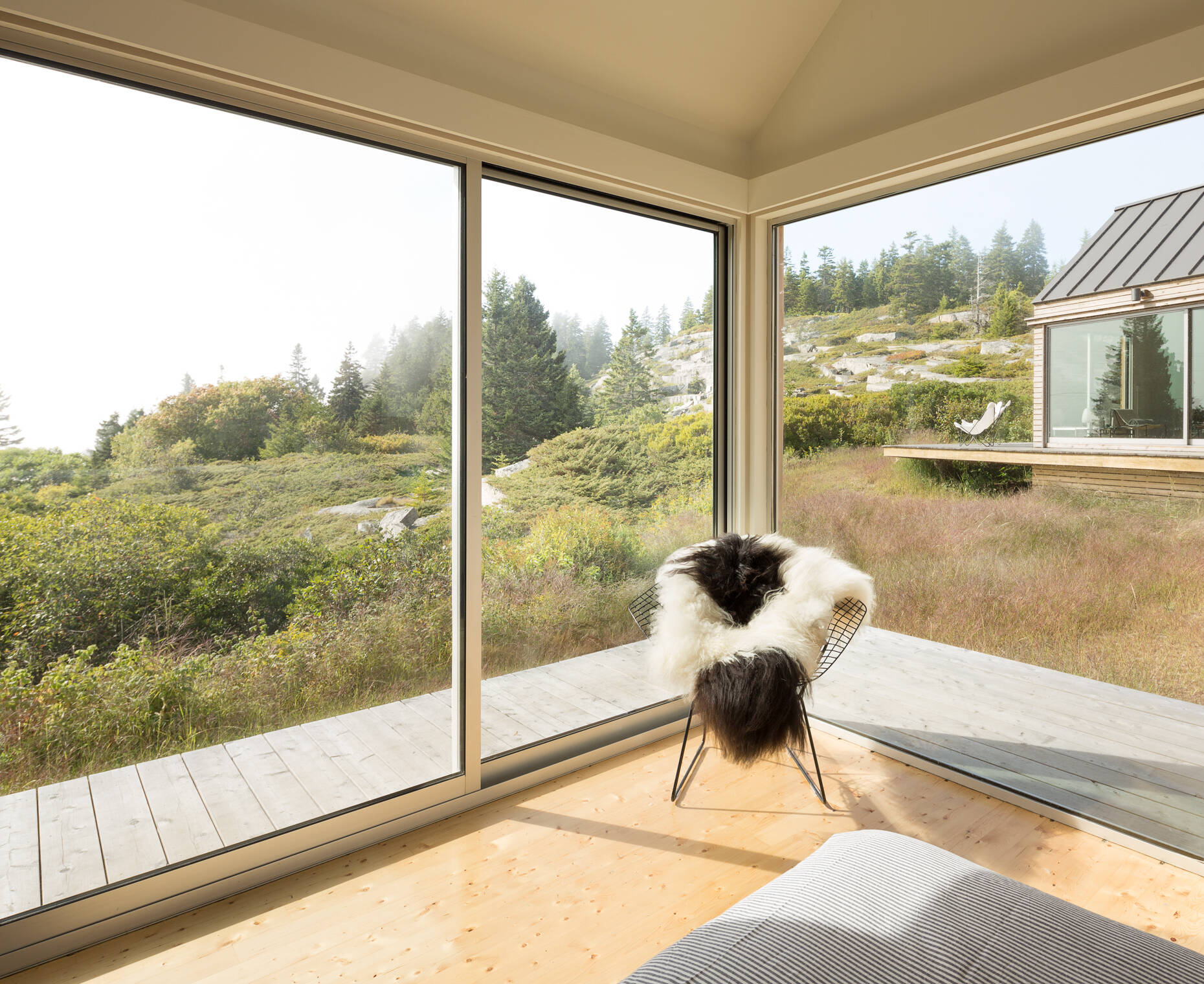 Framed by glass walls and wild views, this bedroom corner blends calm tones, cozy textures, and a deep connection to the landscape.