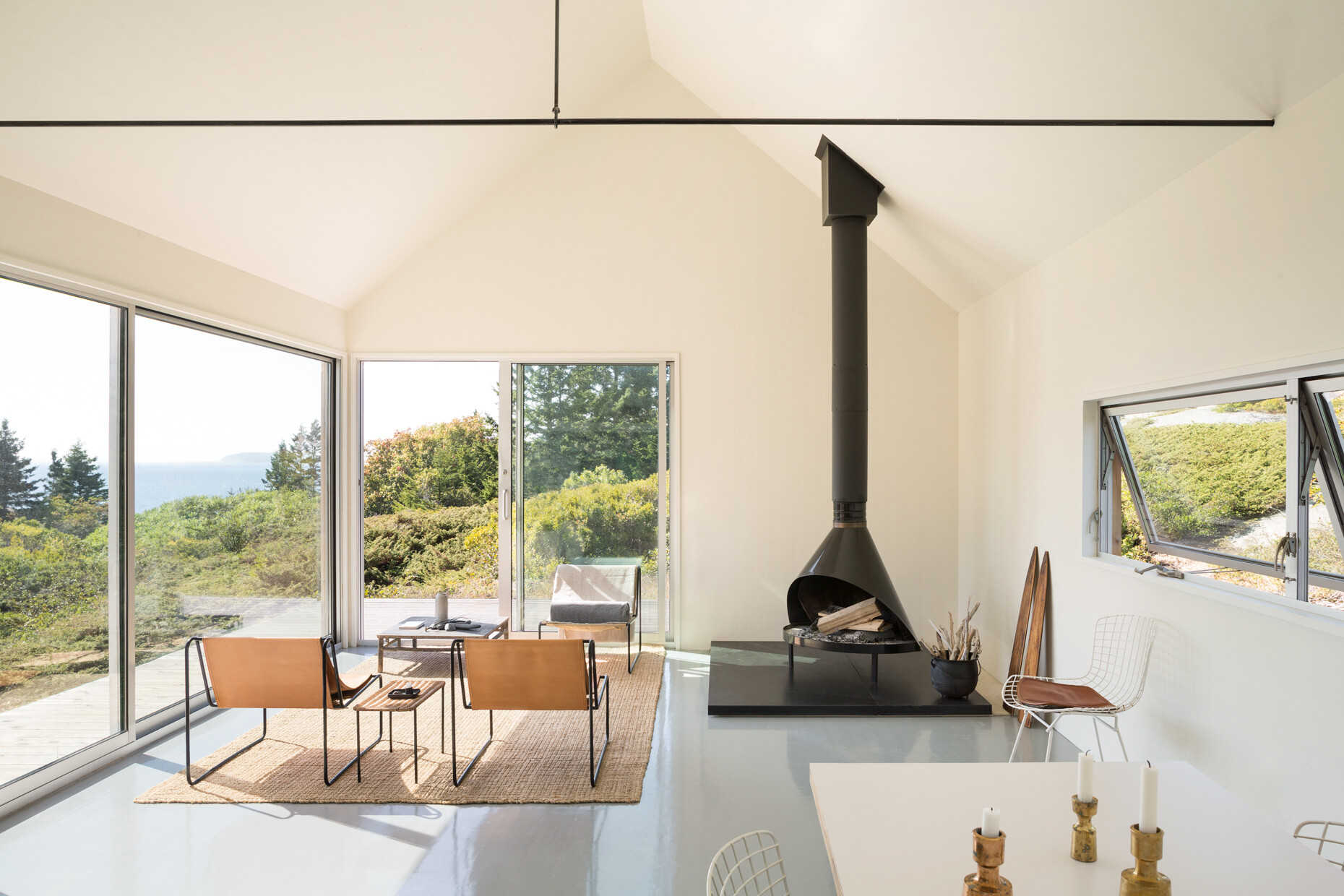 This pared-back living room features soft neutrals, a black fireplace, and full-height glass sliders that blur the line between indoors and out.
