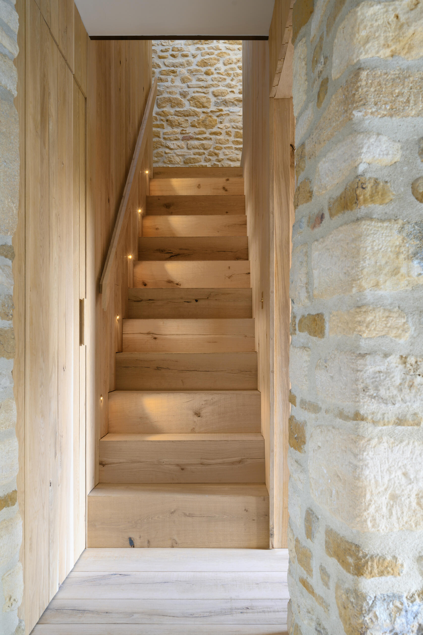 A timber staircase pod is central to the entire layout of this barn conversion. It links the two volumes of the barn, creating a passageway between rooms and housing the new staircase to the first floor. The pod also mediates the level change, helping the house feel cohesive despite the barn’s split levels. Its presence is bold but natural, blending new with old without overwhelming the original structure.