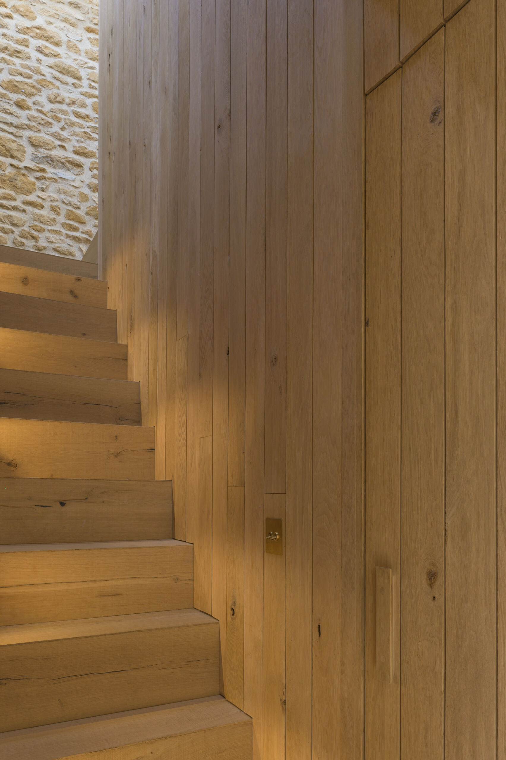 A timber staircase pod is central to the entire layout of this barn conversion. It links the two volumes of the barn, creating a passageway between rooms and housing the new staircase to the first floor. The pod also mediates the level change, helping the house feel cohesive despite the barn’s split levels. Its presence is bold but natural, blending new with old without overwhelming the original structure.