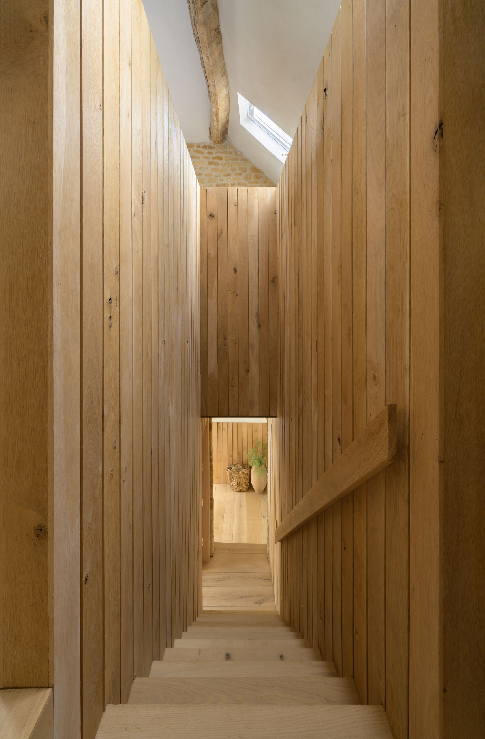 A timber staircase pod is central to the entire layout of this barn conversion. It links the two volumes of the barn, creating a passageway between rooms and housing the new staircase to the first floor. The pod also mediates the level change, helping the house feel cohesive despite the barn’s split levels. Its presence is bold but natural, blending new with old without overwhelming the original structure.