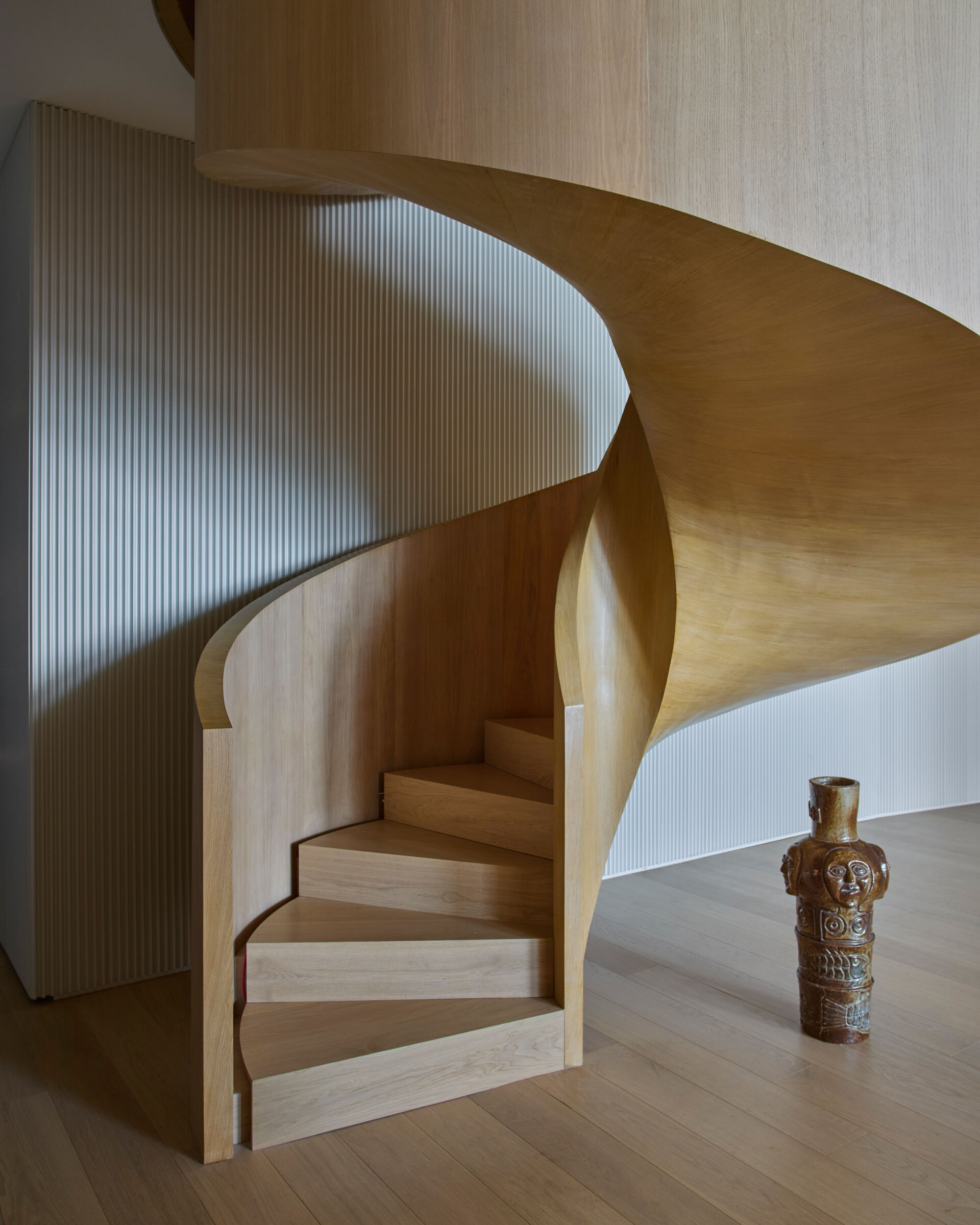 The staircase, originally located in a corner, was relocated to the center of the duplex. Redesigned as a wood spiral, it functions as a sculptural feature that organizes movement between floors while reinforcing the apartment’s sense of fluidity and connection.