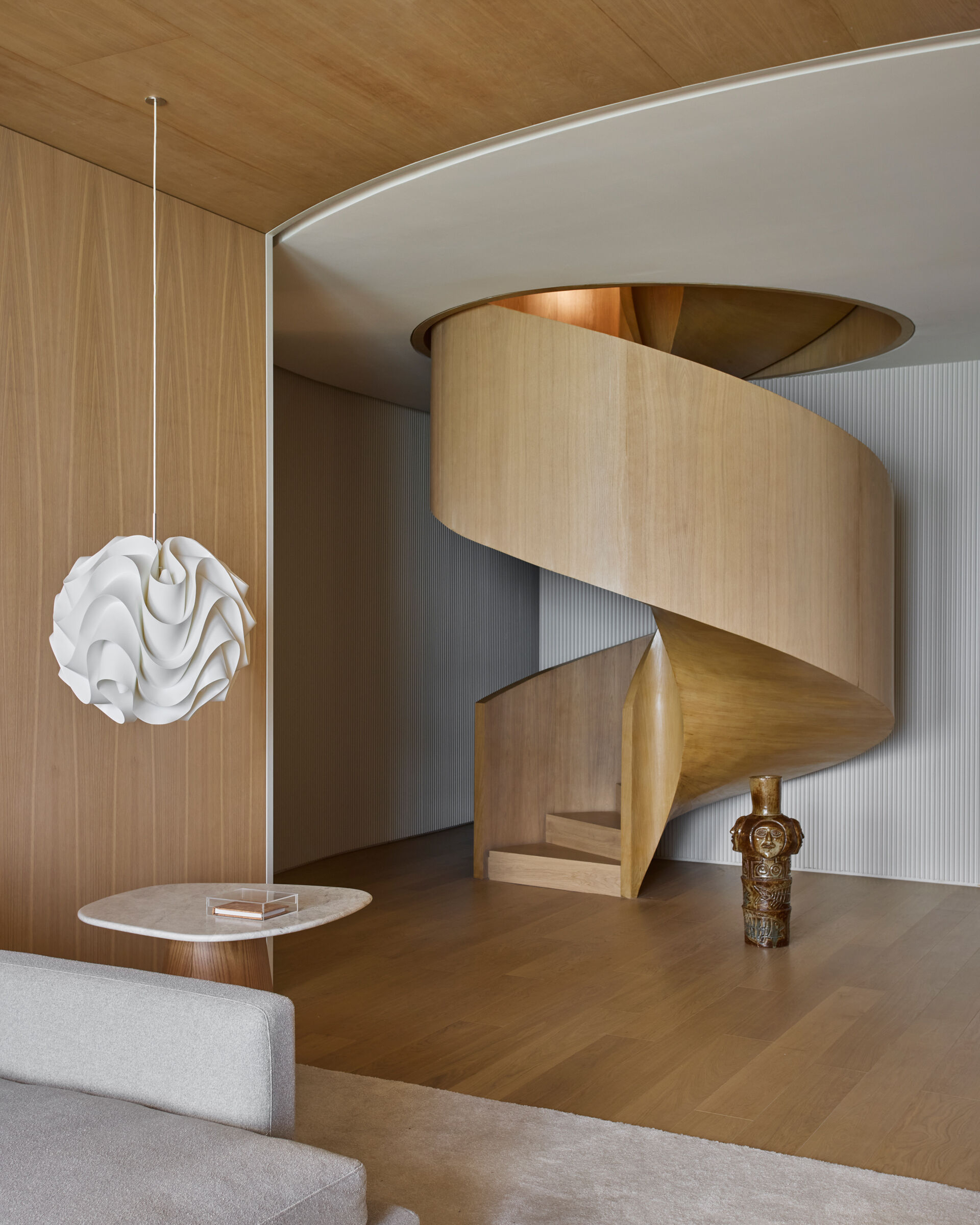 The staircase, originally located in a corner, was relocated to the center of the duplex. Redesigned as a wood spiral, it functions as a sculptural feature that organizes movement between floors while reinforcing the apartment’s sense of fluidity and connection.