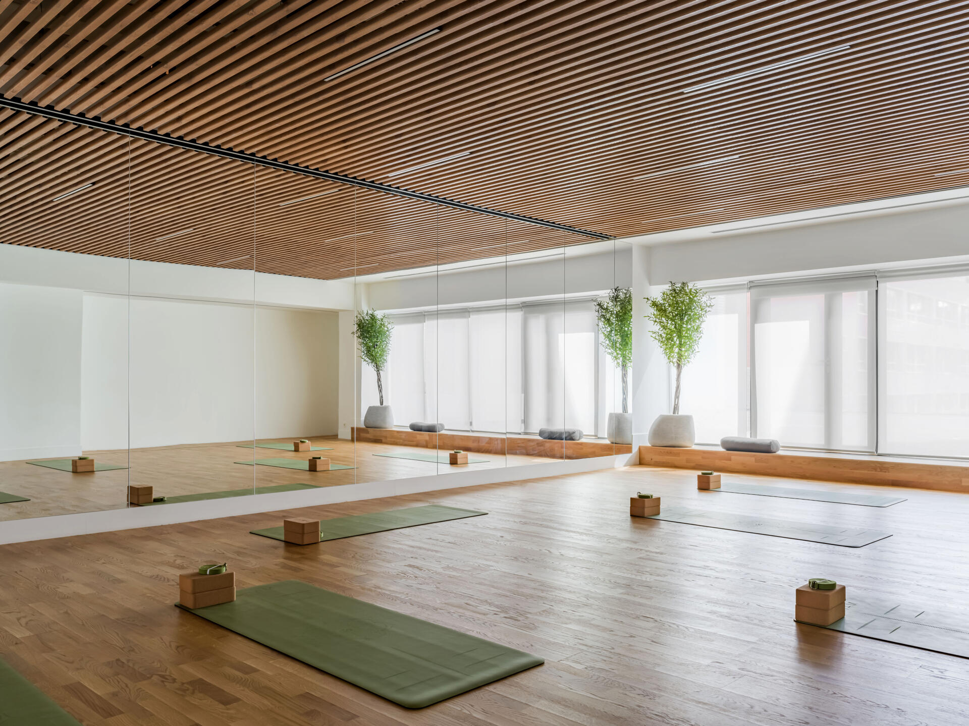 The second floor of SIAM SPA takes on a more minimalist mood with smooth grey walls, veined wood accents, and lush greenery. Custom wooden fitness equipment blends beauty with function, offering a serene environment for stretching, strength, and movement.