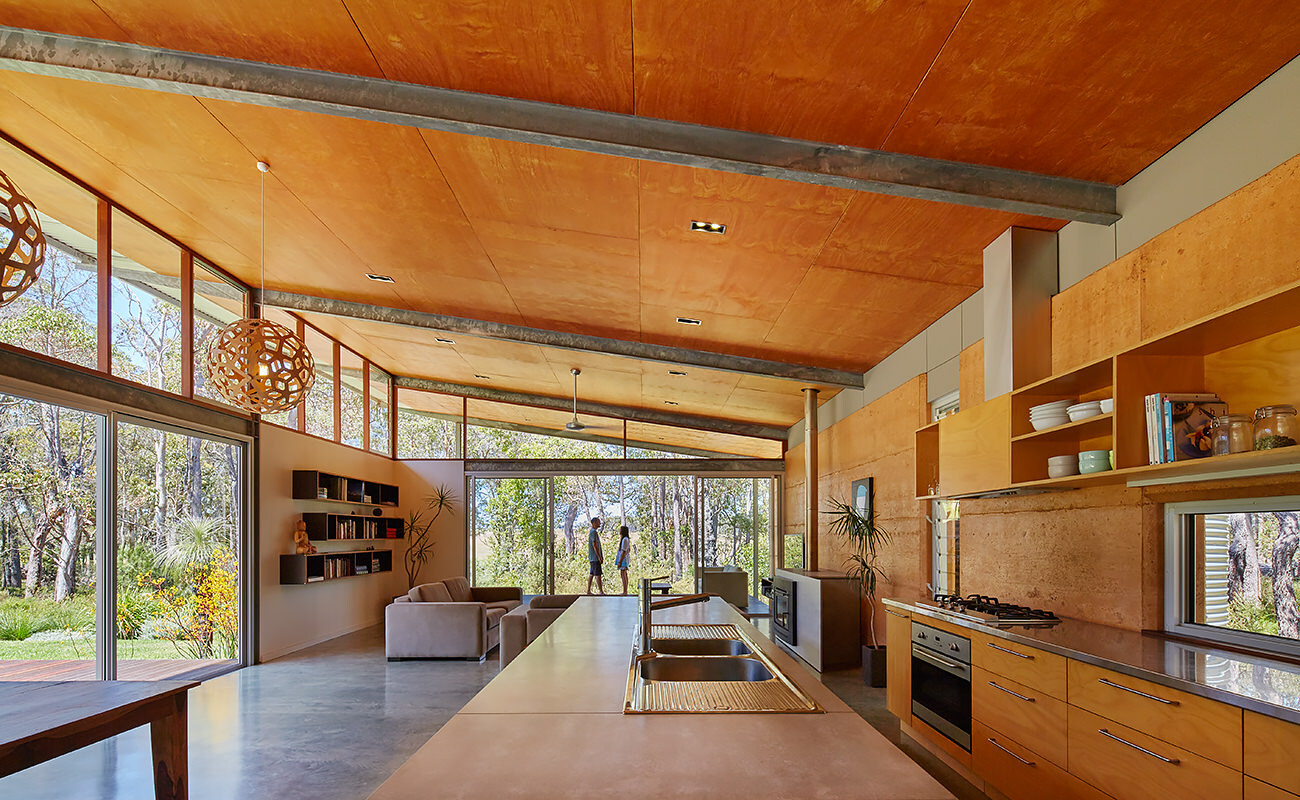 Timber-lined ceilings, a rammed earth wall, and natural materials create a warm, open interior that feels both grounded and connected to the bush.