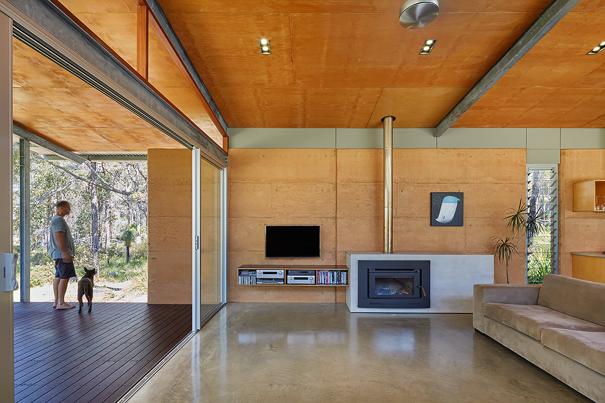 Timber-lined ceilings, a rammed earth wall, and natural materials create a warm, open interior that feels both grounded and connected to the bush.