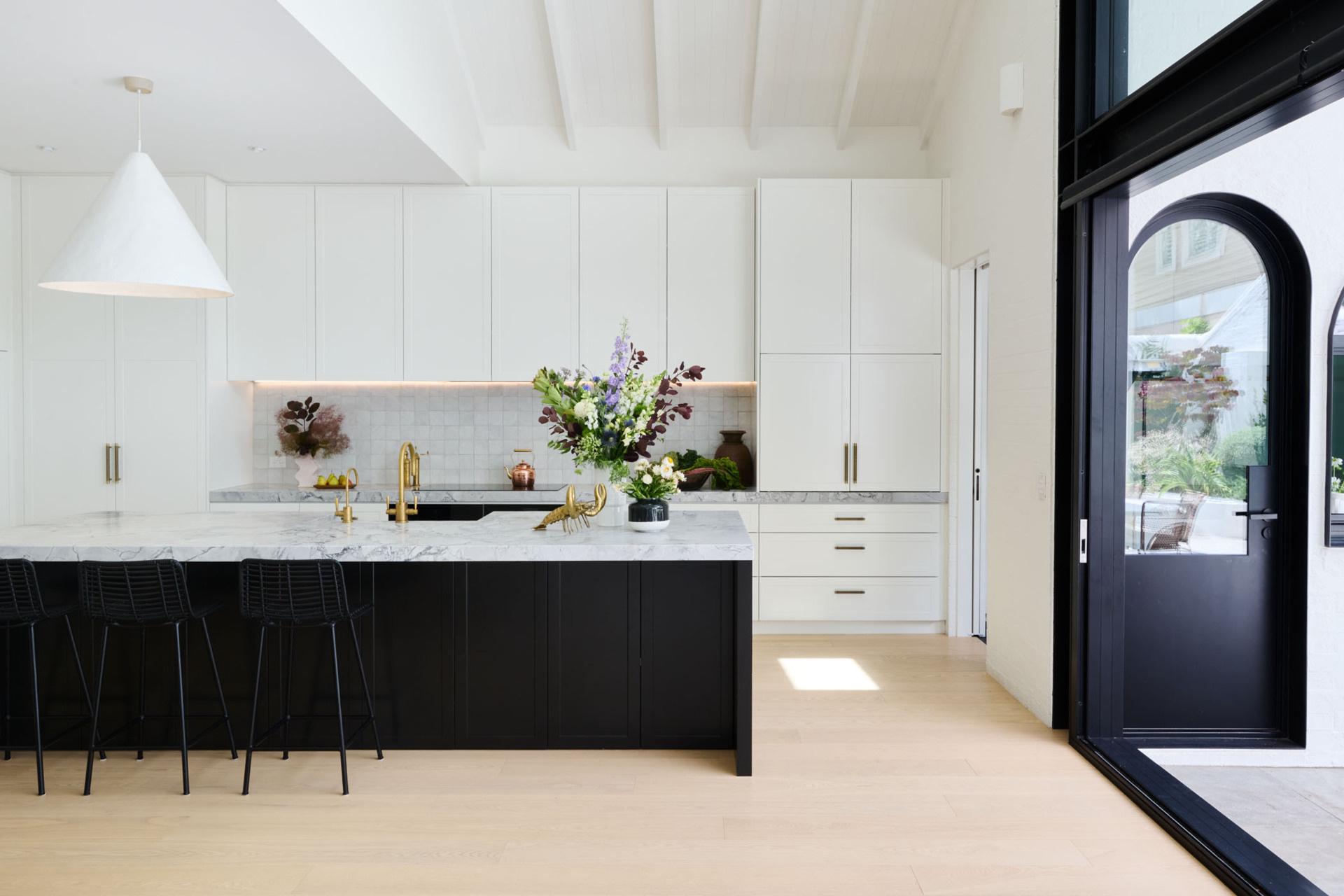 Soft, Scandinavian-inspired details and a minimalist black-and-white palette create a calm, functional kitchen that opens directly to the garden.
