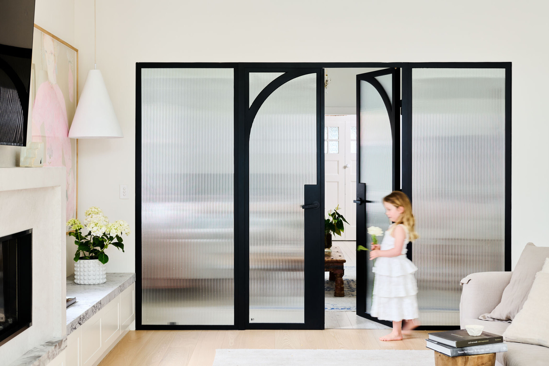 Steel-framed glass doors with fluted panels and arched detailing elegantly divide space while keeping the light flowing. A beautiful blend of privacy and style.