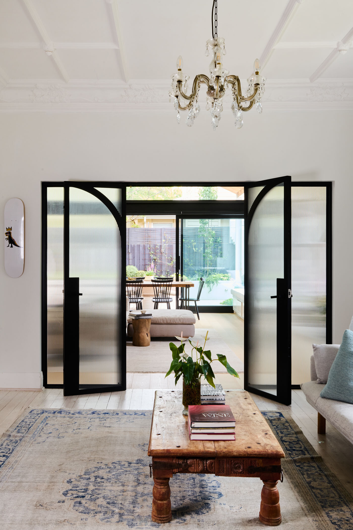 Steel-framed glass doors with fluted panels and arched detailing elegantly divide space while keeping the light flowing. A beautiful blend of privacy and style.