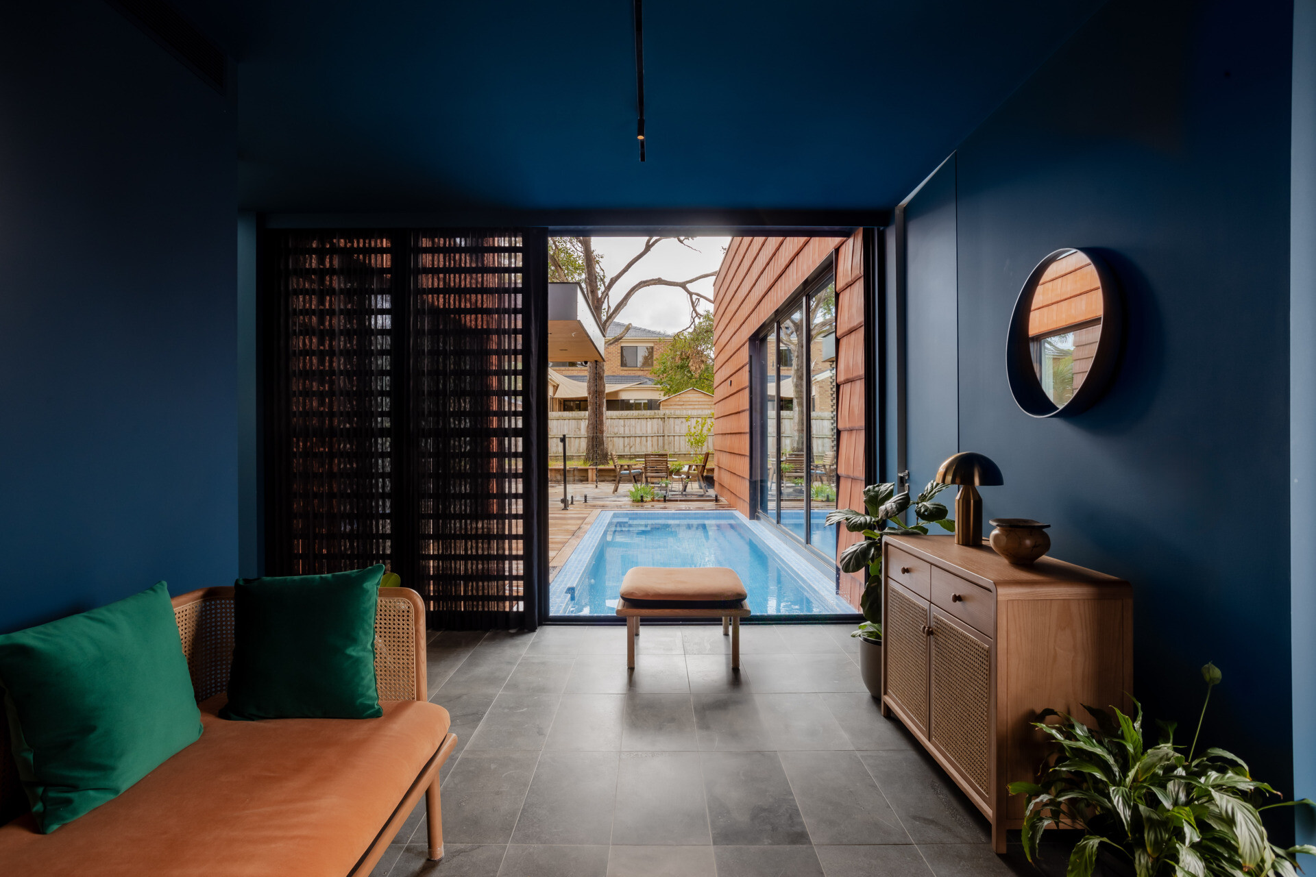 Step inside to a bold blue entryway that opens to a surprise view of the courtyard and pool, a moment of drama softened by natural curves and tones.
