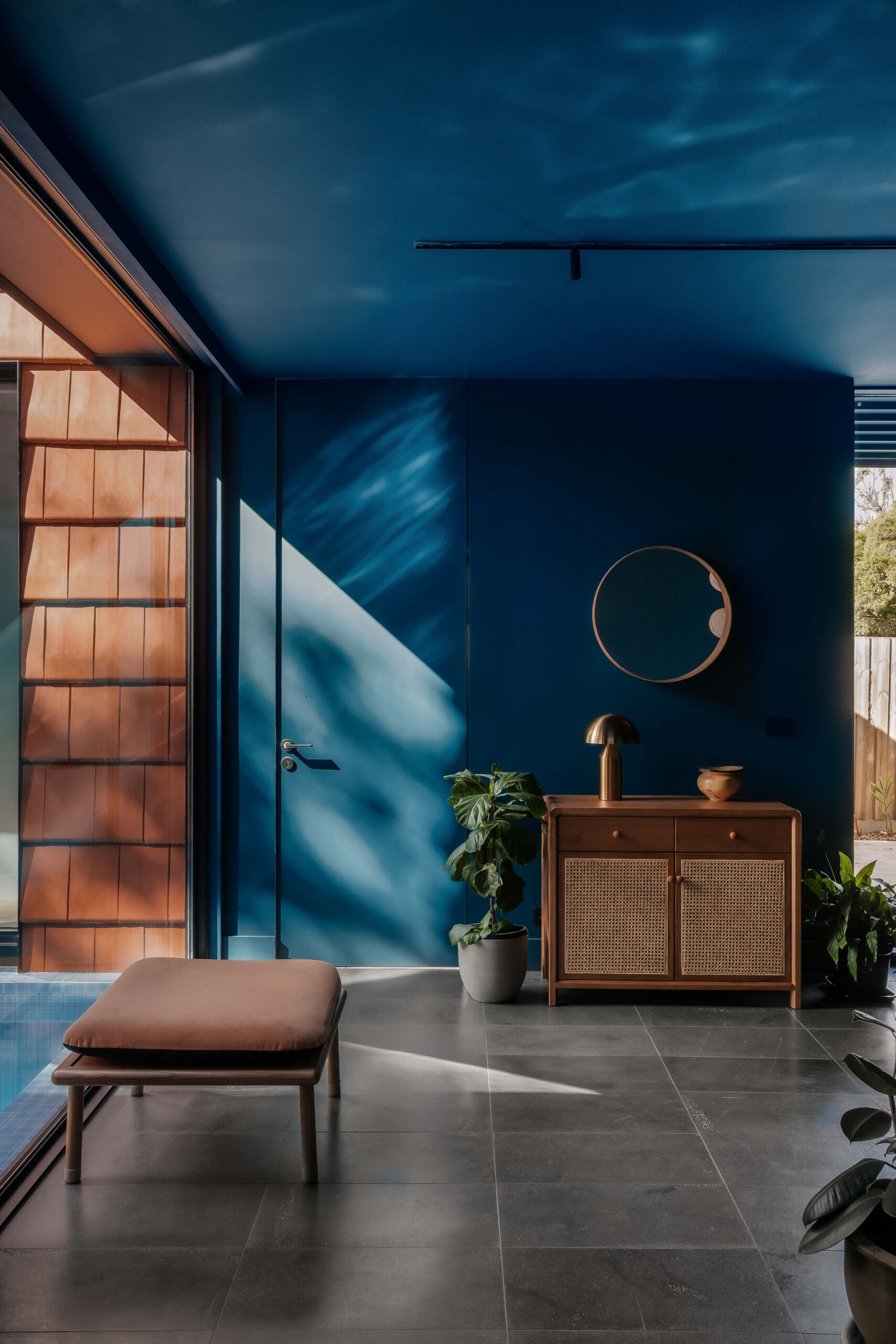 Step inside to a bold blue entryway that opens to a surprise view of the courtyard and pool, a moment of drama softened by natural curves and tones.