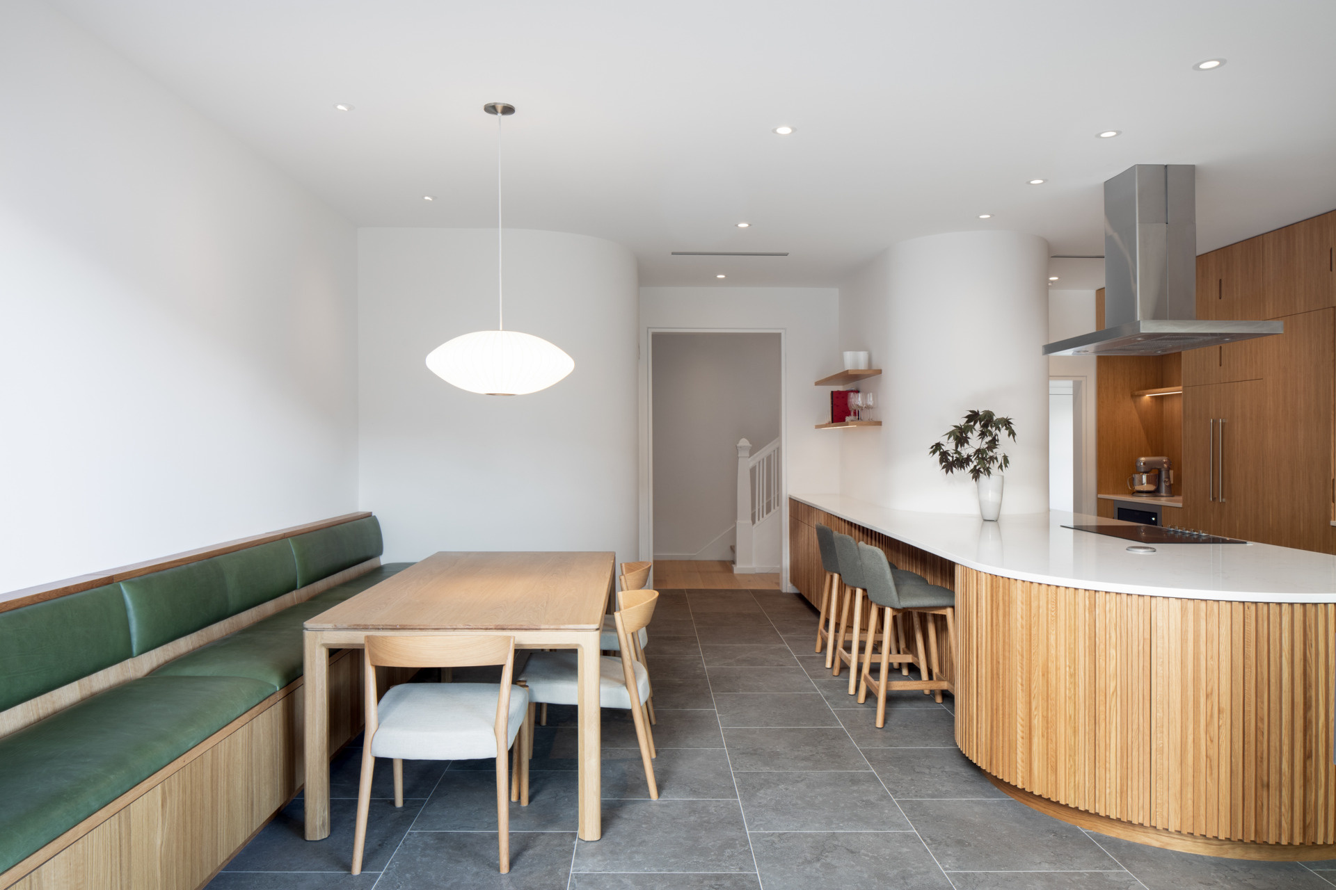 This built-in oak banquette anchors a cozy dining area, with rounded joinery, hidden storage, and soft natural light enhancing the sense of calm and connection.