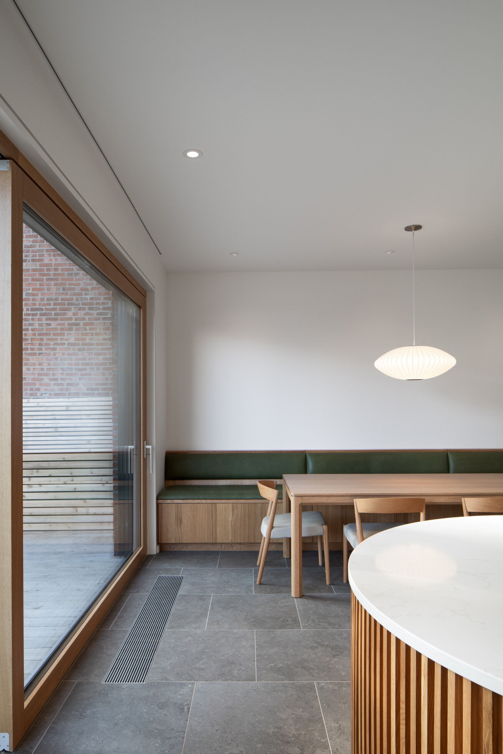 This built-in oak banquette anchors a cozy dining area, with rounded joinery, hidden storage, and soft natural light enhancing the sense of calm and connection.
