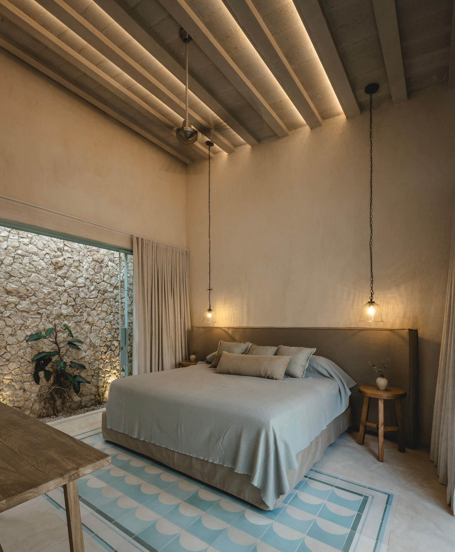 A contemporary bedroom with a wide headboard, and steel-framed glass walls that open to the outdoors.