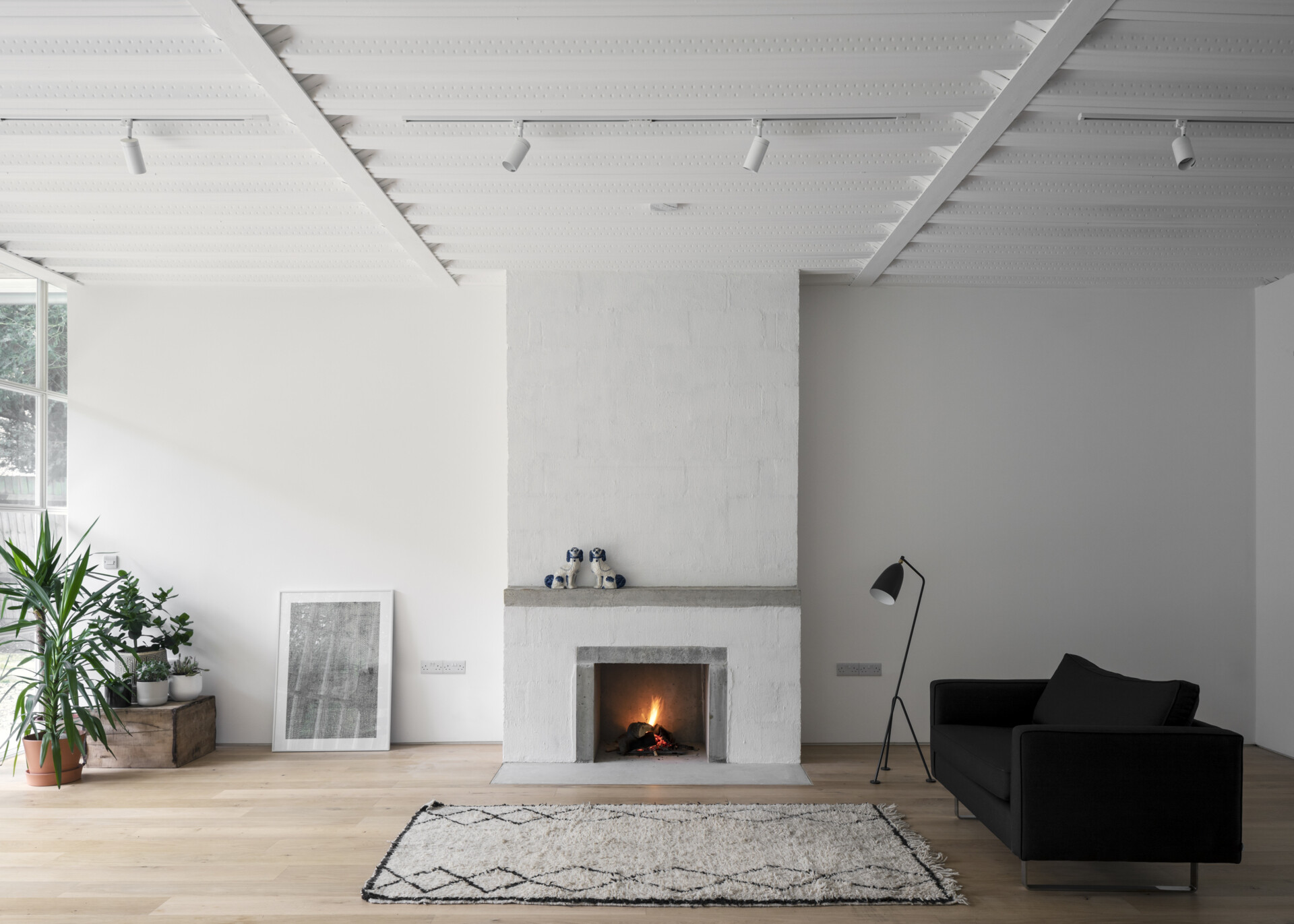 A minimalist fireplace grounds the living area with quiet strength, tying together the home’s raw materials and relaxed, modern feel.