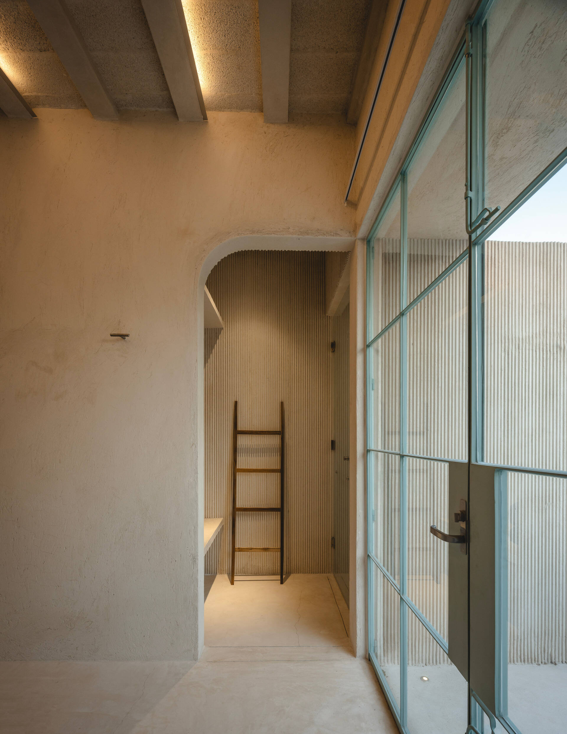 Upstairs, glass walls and doors, framed in slender steel and painted in a sky-blue tone, add a sense of transparency and lightness, opening each room to the patios and gardens beyond.