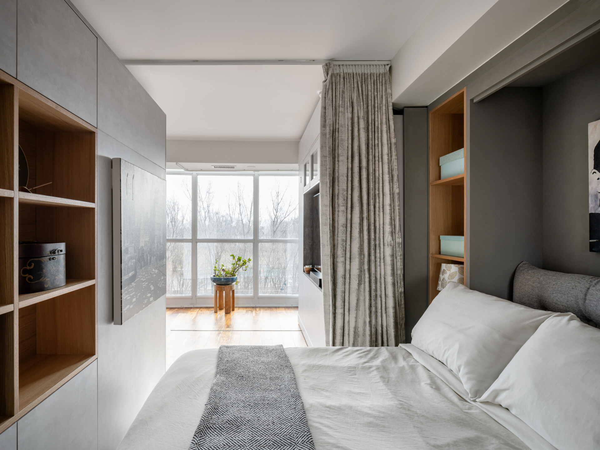 A modern apartment has clever movable walls, packed with storage, a desk, and entertainment features. Behind the walls is a space that gets transformed into a bedroom.