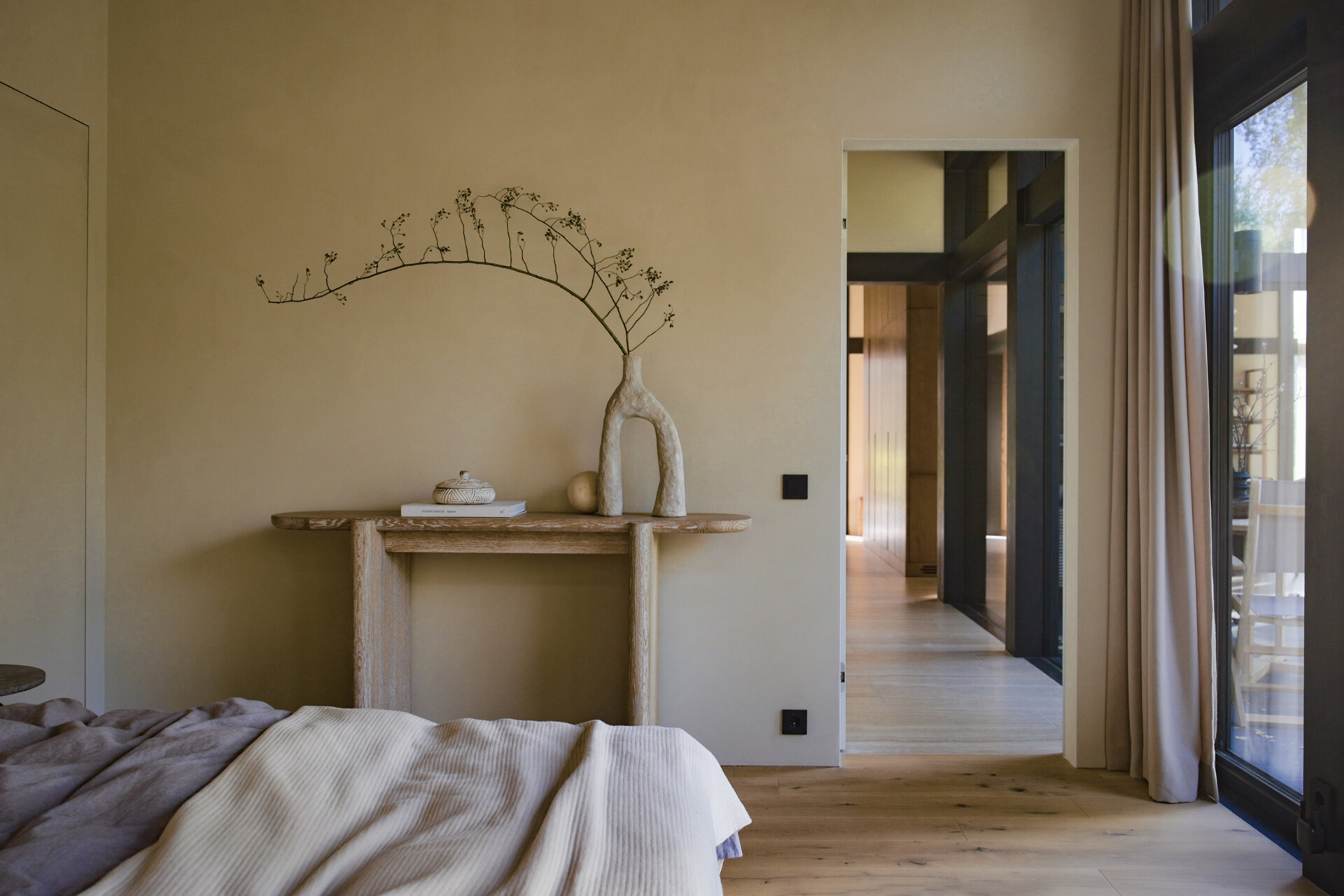 Textured stone, ribbed wood, and clean-lined furniture define this light-filled bedroom with panoramic views and a calming material palette.