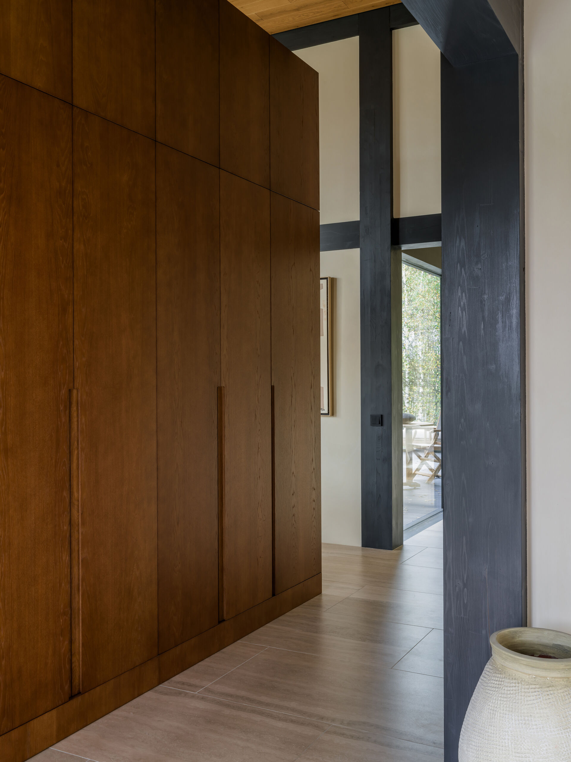 This quiet entryway uses a custom kitchen partition and hidden storage to keep the space clean and open without blocking light or flow.