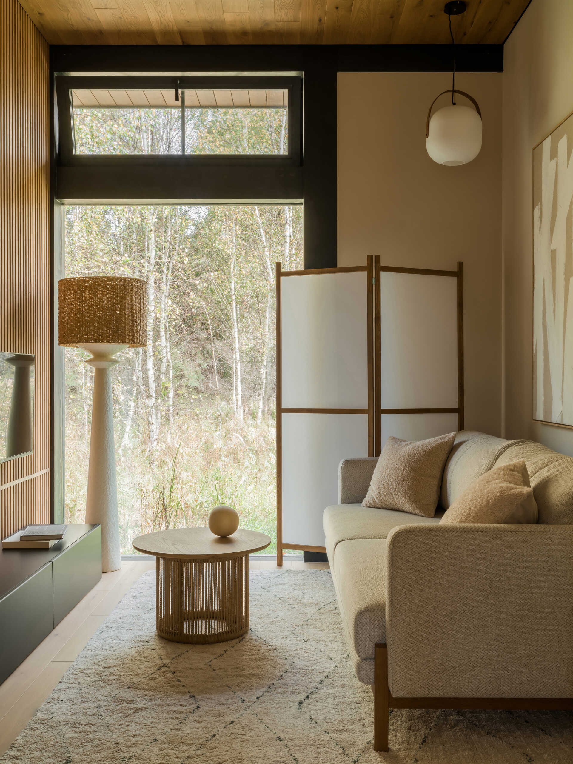 A multifunctional study zone features a compact sofa, a woven side table, and a shoji-style screen for soft light and privacy.