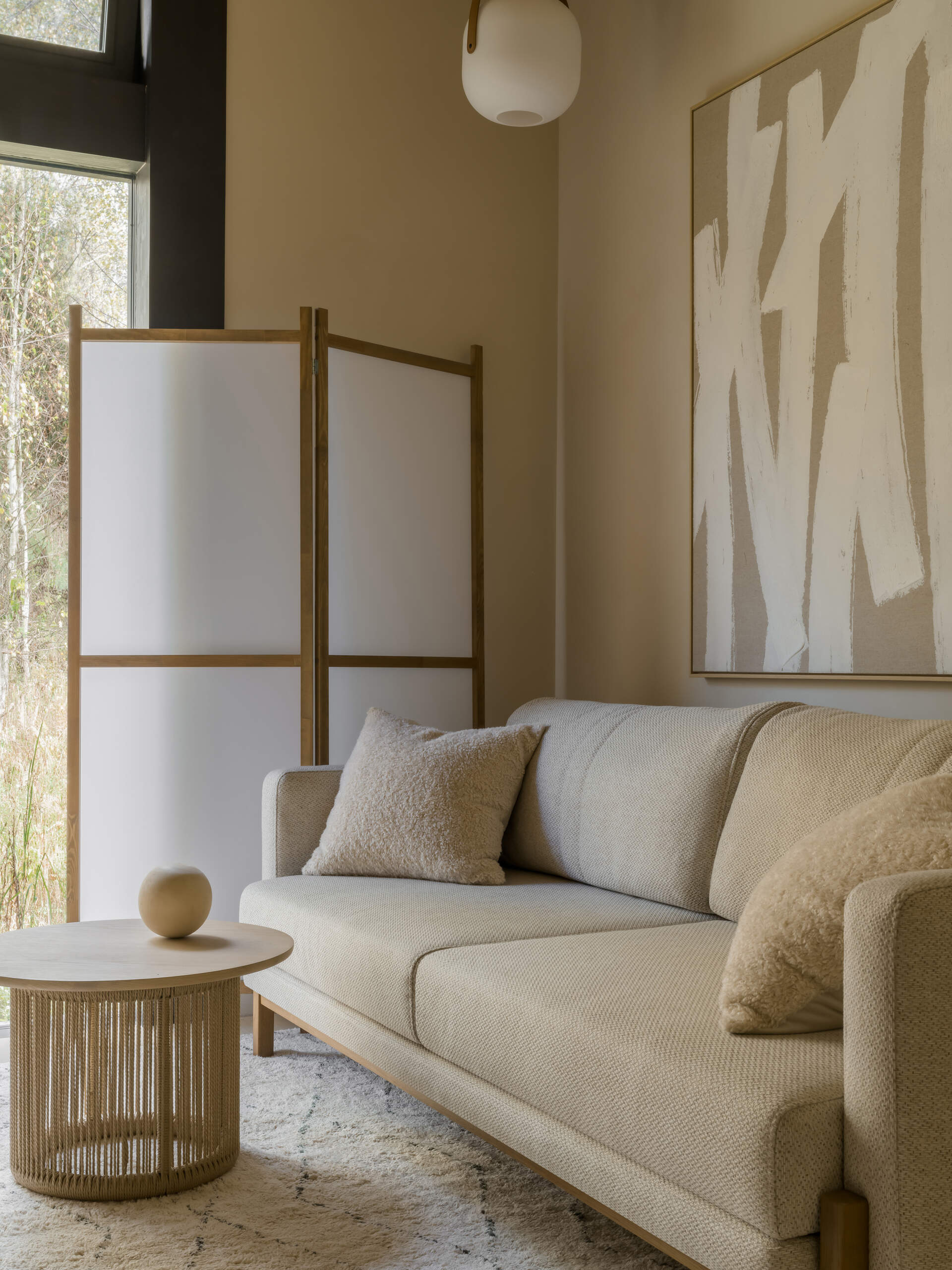 A multifunctional study zone features a compact sofa, a woven side table, and a shoji-style screen for soft light and privacy.