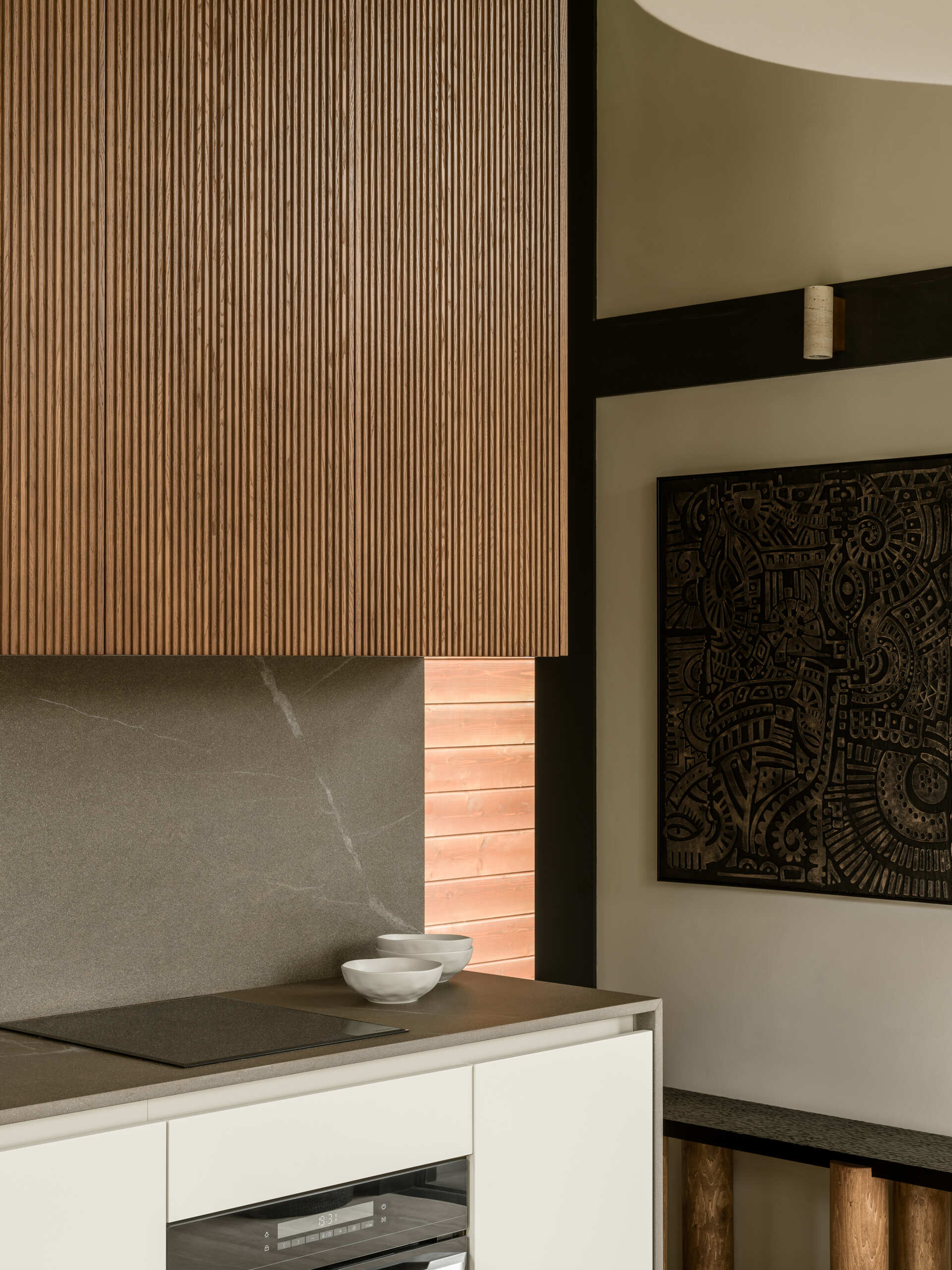 A sculptural, amber-toned kitchen unit by Dantone Home anchors the layout, blending beauty and function with warm wood textures and smart storage.