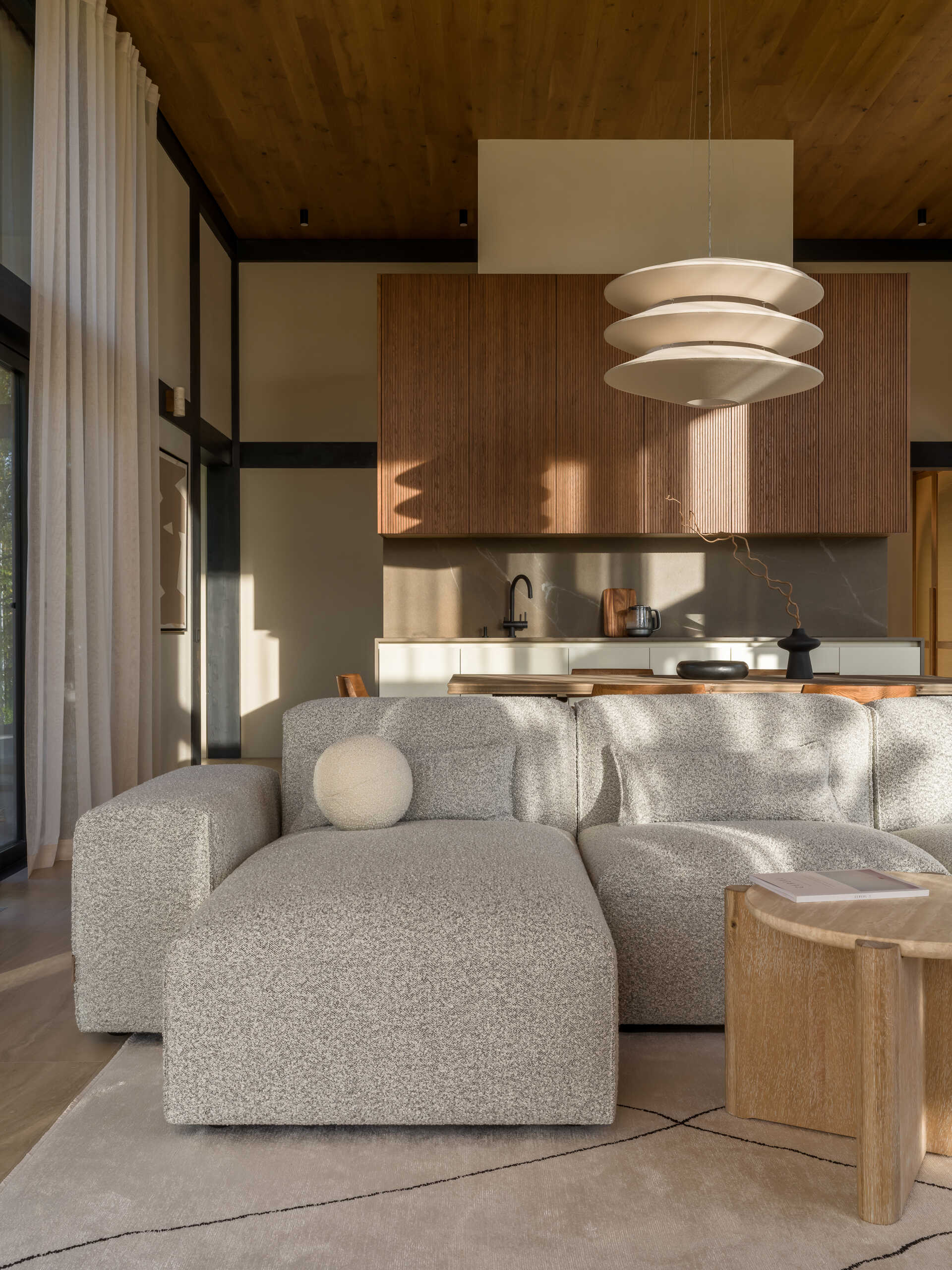 A modular sofa and stone-inspired coffee table bring softness and structure to this living room, framed by views of the surrounding landscape.