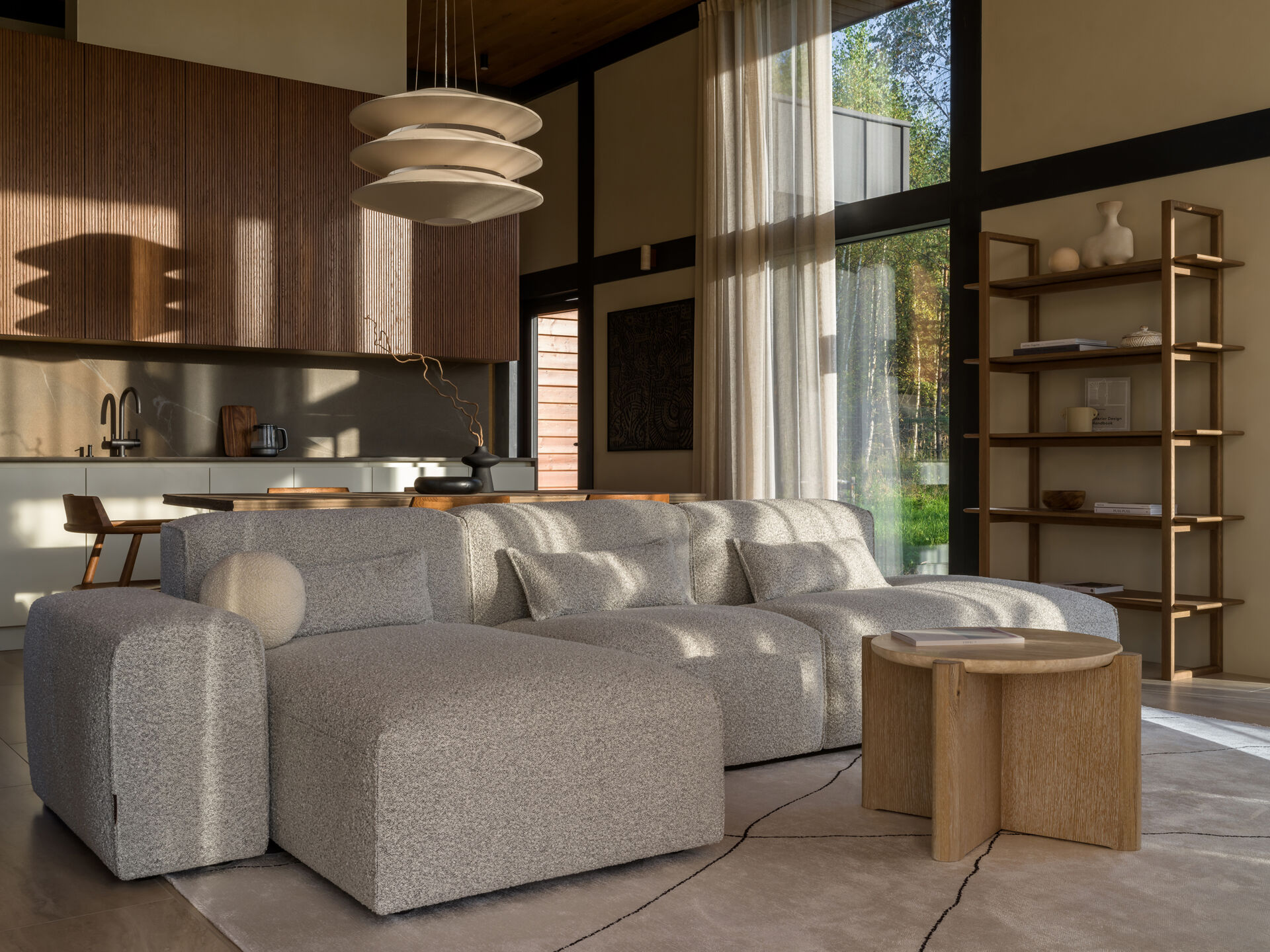 A modular sofa and stone-inspired coffee table bring softness and structure to this living room, framed by views of the surrounding landscape.