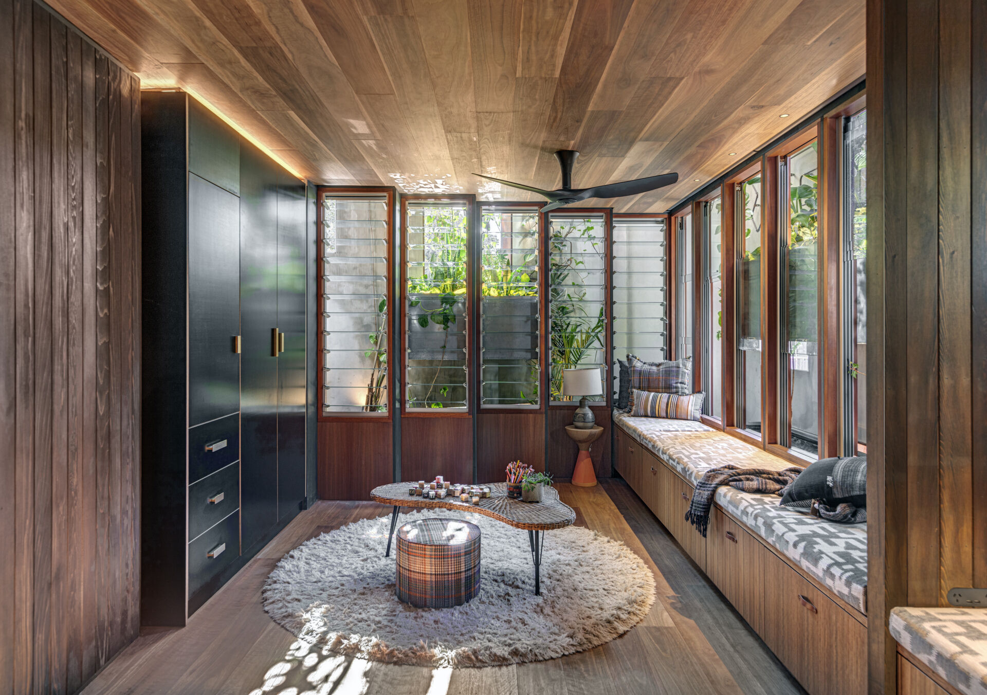 The kids’ room balances warmth and utility with built-in bunk beds, and cabinetry that keeps the space tidy. A long window seat offers a quiet spot to read, while soft rugs and low tables encourage play and creativity in a calm, light-filled setting.