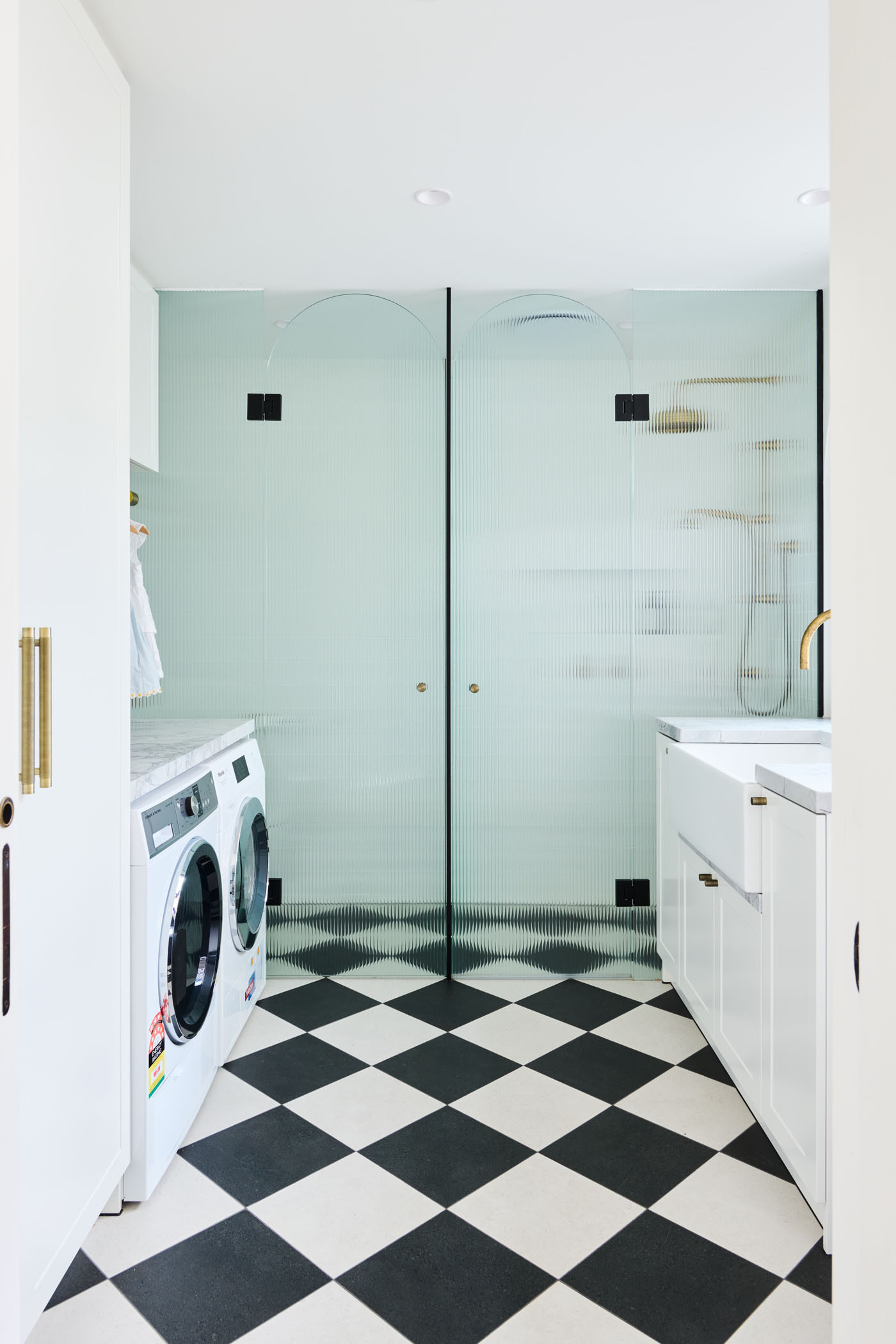 The checkerboard floor in this combined bathroom and laundry room adds a playful twist to the otherwise minimalist interiors. A perfect example of functional design with personality.