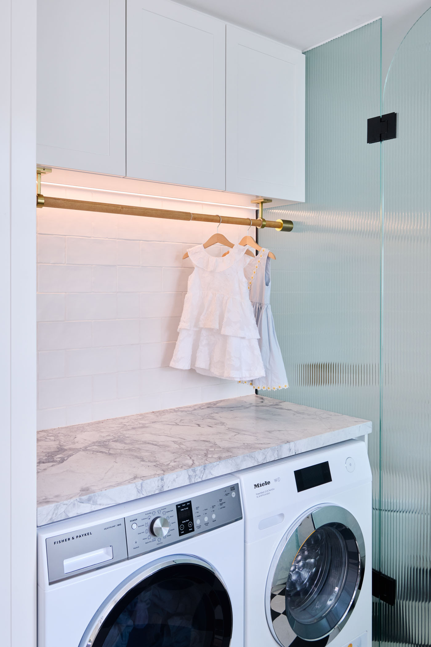 The checkerboard floor in this combined bathroom and laundry room adds a playful twist to the otherwise minimalist interiors. A perfect example of functional design with personality.
