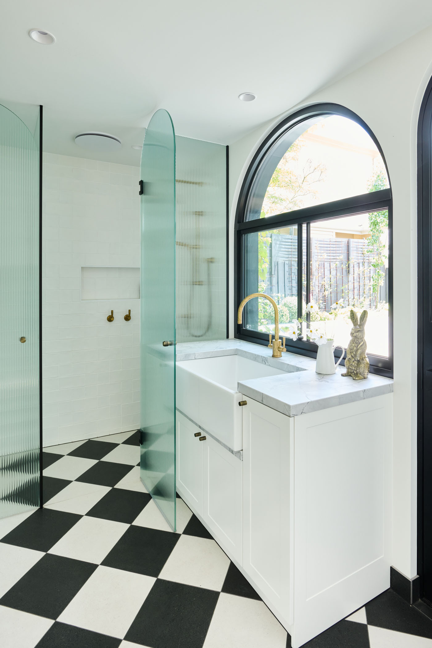 The checkerboard floor in this combined bathroom and laundry room adds a playful twist to the otherwise minimalist interiors. A perfect example of functional design with personality.