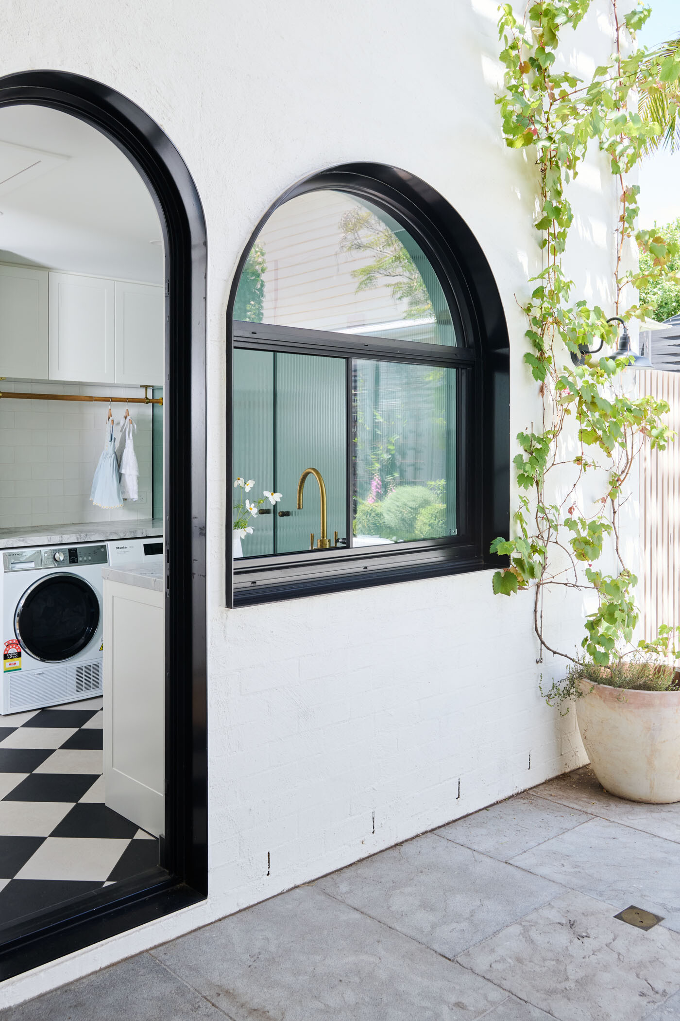 The checkerboard floor in this combined bathroom and laundry room adds a playful twist to the otherwise minimalist interiors. A perfect example of functional design with personality.
