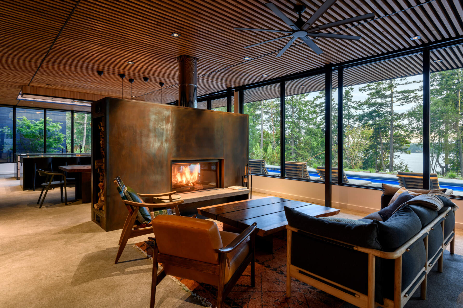 Large windows and a corten steel fireplace anchor this open, light-filled living space with views to the water.