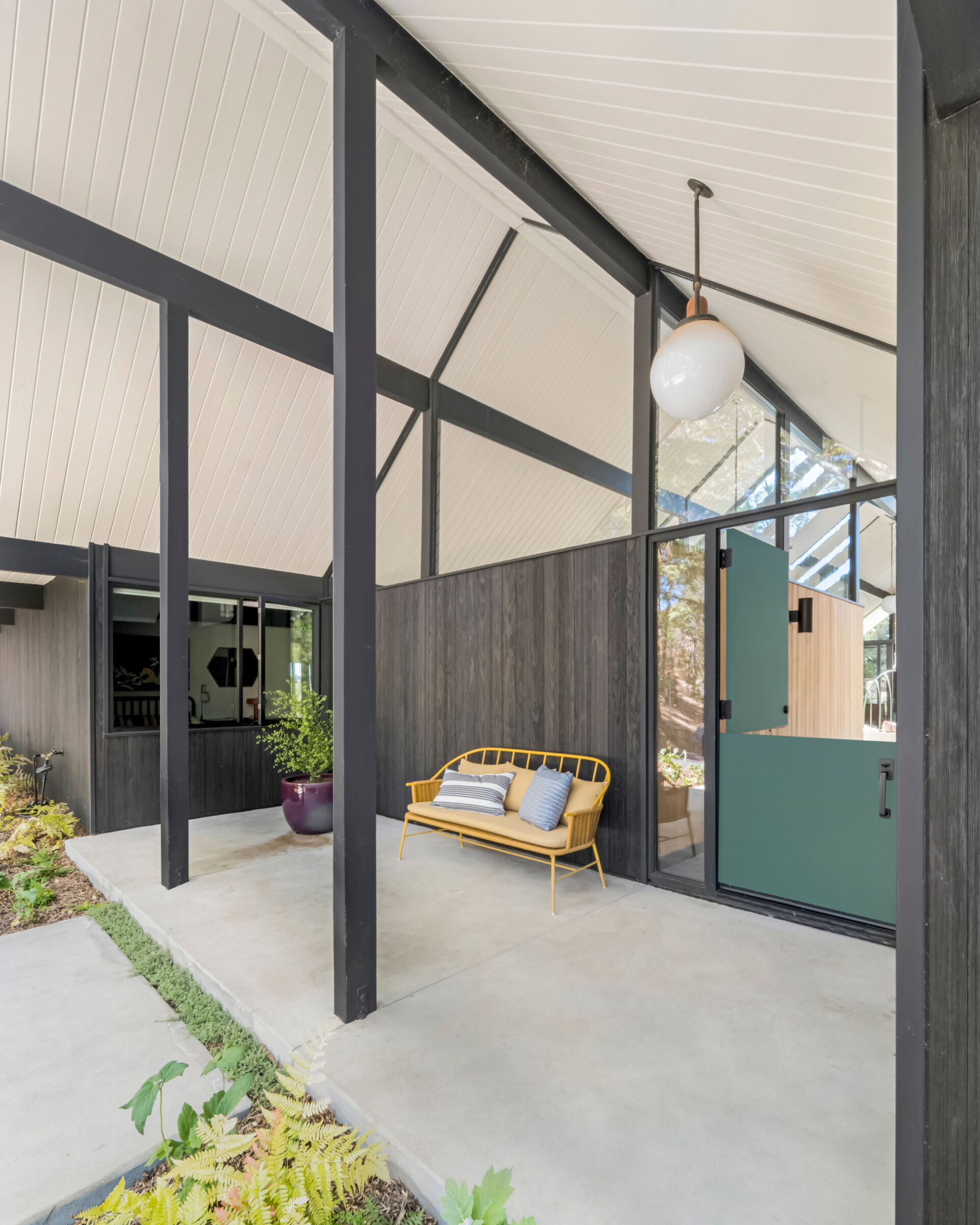 The entry porch sits beneath the gable, where transom windows bring in natural light and frame the signature Eichler post-and-beam construction. A custom Dutch door by Gustave Carlson greets visitors, a recurring motif in his residential work and a nod to craftsmanship and functionality.