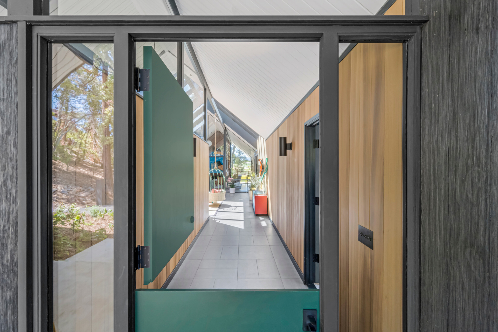 The entry porch sits beneath the gable, where transom windows bring in natural light and frame the signature Eichler post-and-beam construction. A custom Dutch door by Gustave Carlson greets visitors, a recurring motif in his residential work and a nod to craftsmanship and functionality.