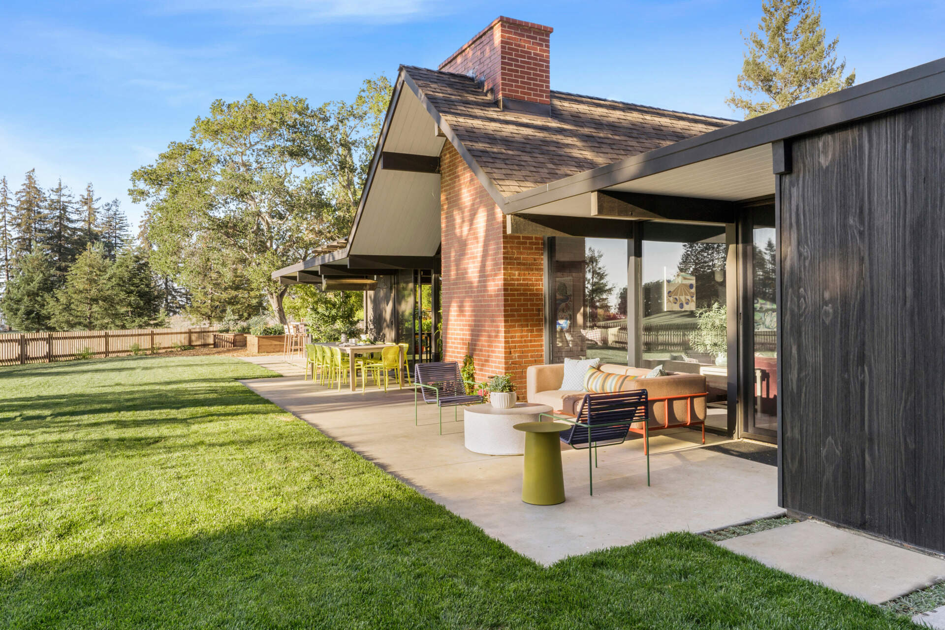 Set back from the street and accessed via a long driveway, the residence combines privacy with striking form. Its exterior has been updated using Shou Sugi Ban Accoya barn wood siding, adding texture and durability. A central gabled roof defines the structure, flanked by two flat-roofed wings that retain the home's mid-century profile.