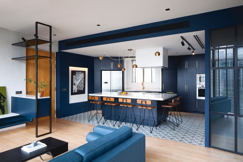 Cobalt blue walls and cabinets unify the kitchen and dining zone, with brass accents and patterned tile adding character.