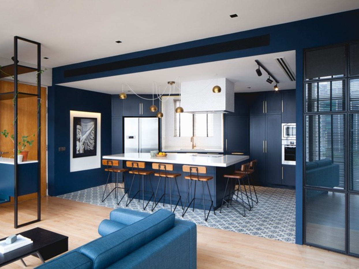 Cobalt blue walls and cabinets unify the kitchen and dining zone, with brass accents and patterned tile adding character.