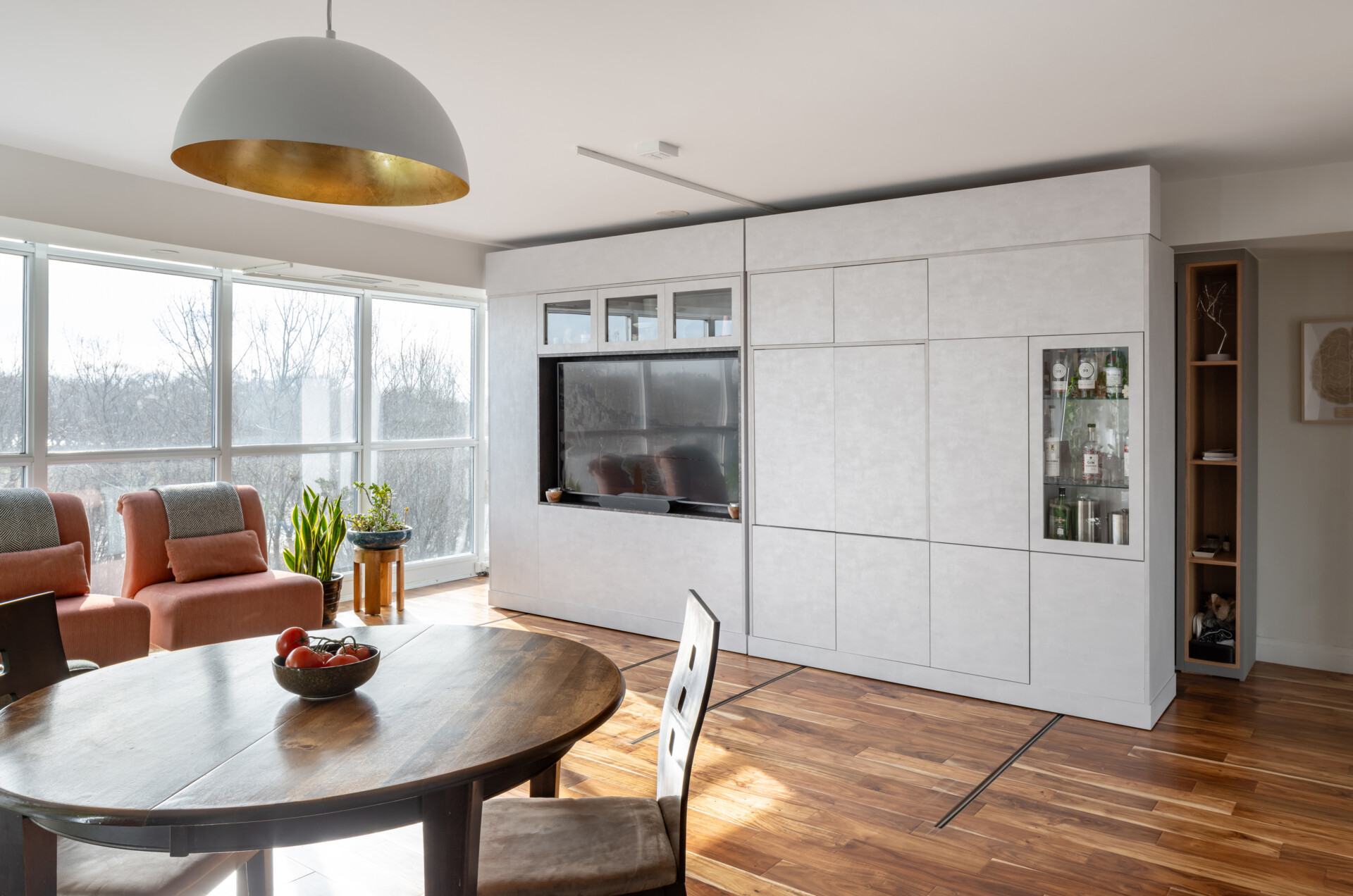 A modern apartment has clever movable walls, packed with storage, a desk, and entertainment features. Behind the walls is a space that gets transformed into a bedroom.