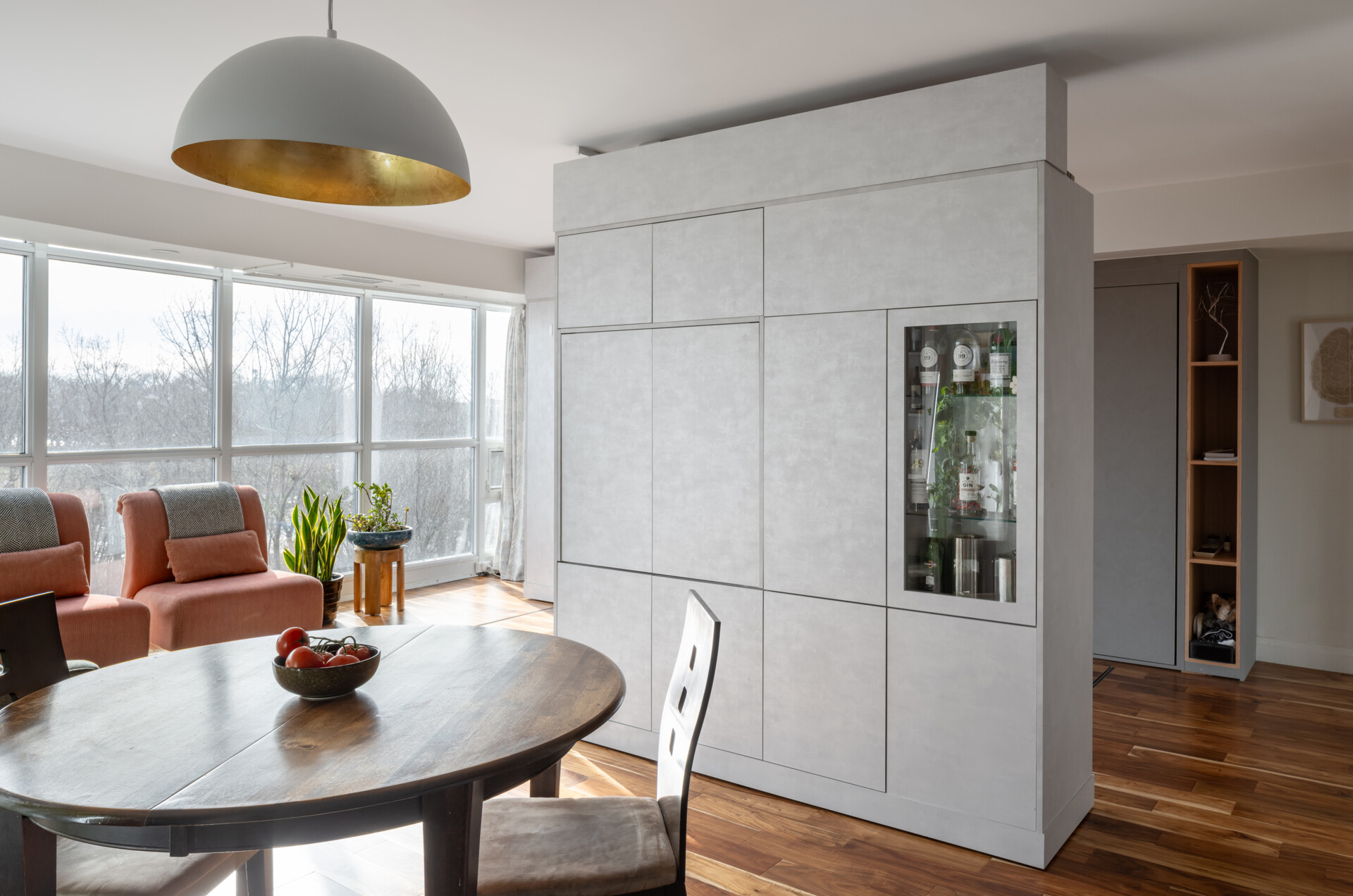 A modern apartment has clever movable walls, packed with storage, a desk, and entertainment features. Behind the walls is a space that gets transformed into a bedroom.
