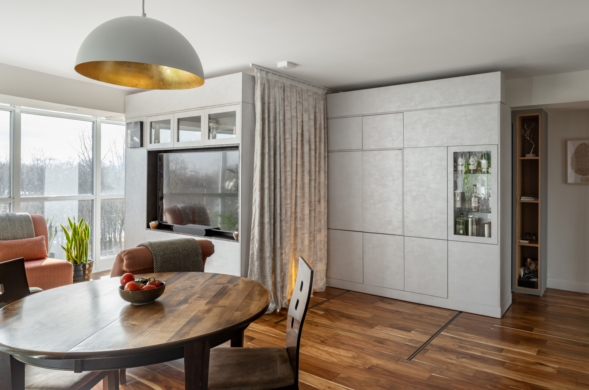 A modern apartment has clever movable walls, packed with storage, a desk, and entertainment features. Behind the walls is a space that gets transformed into a bedroom.