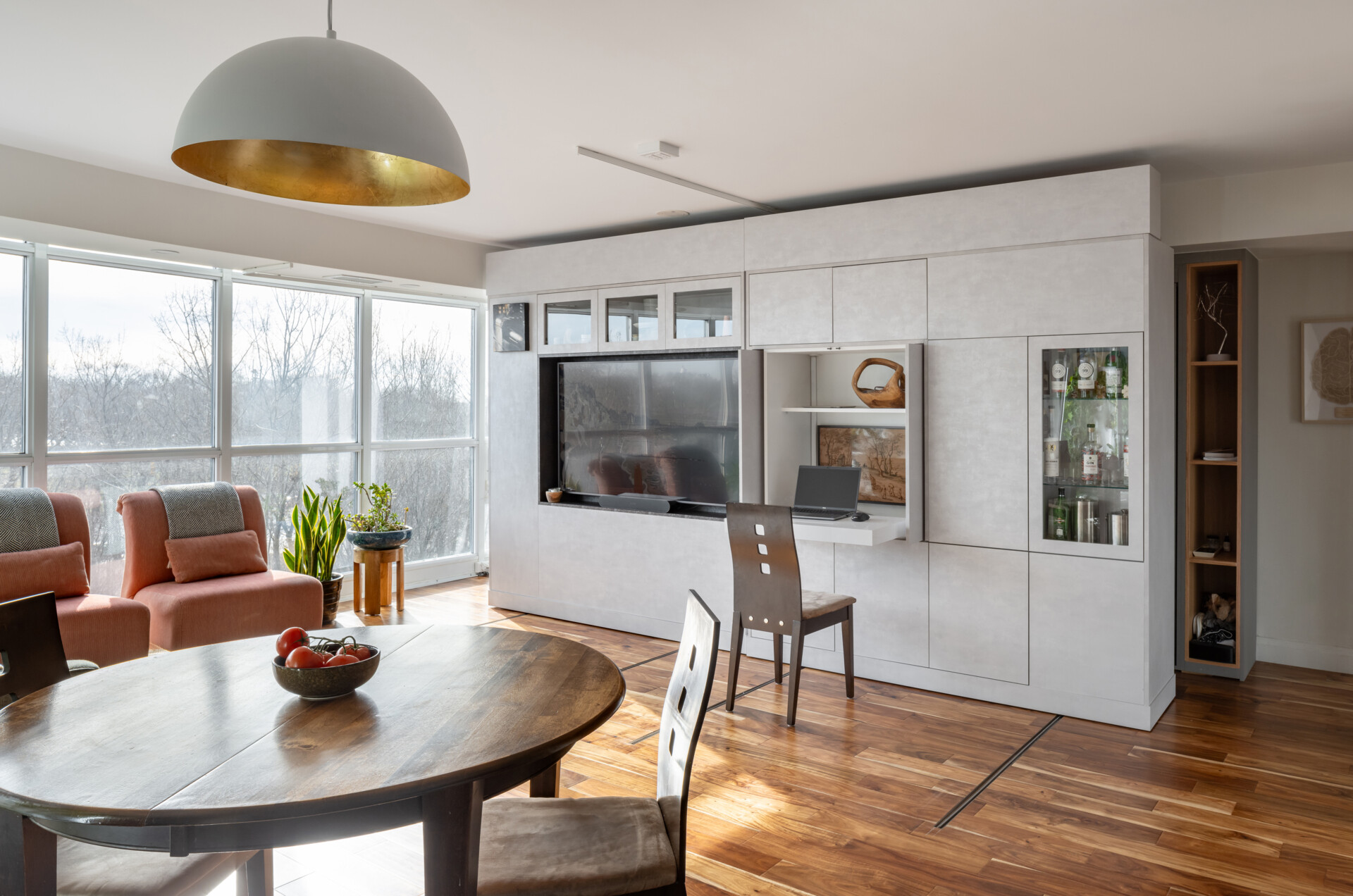 A modern apartment has clever movable walls, packed with storage, a desk, and entertainment features. Behind the walls is a space that gets transformed into a bedroom.