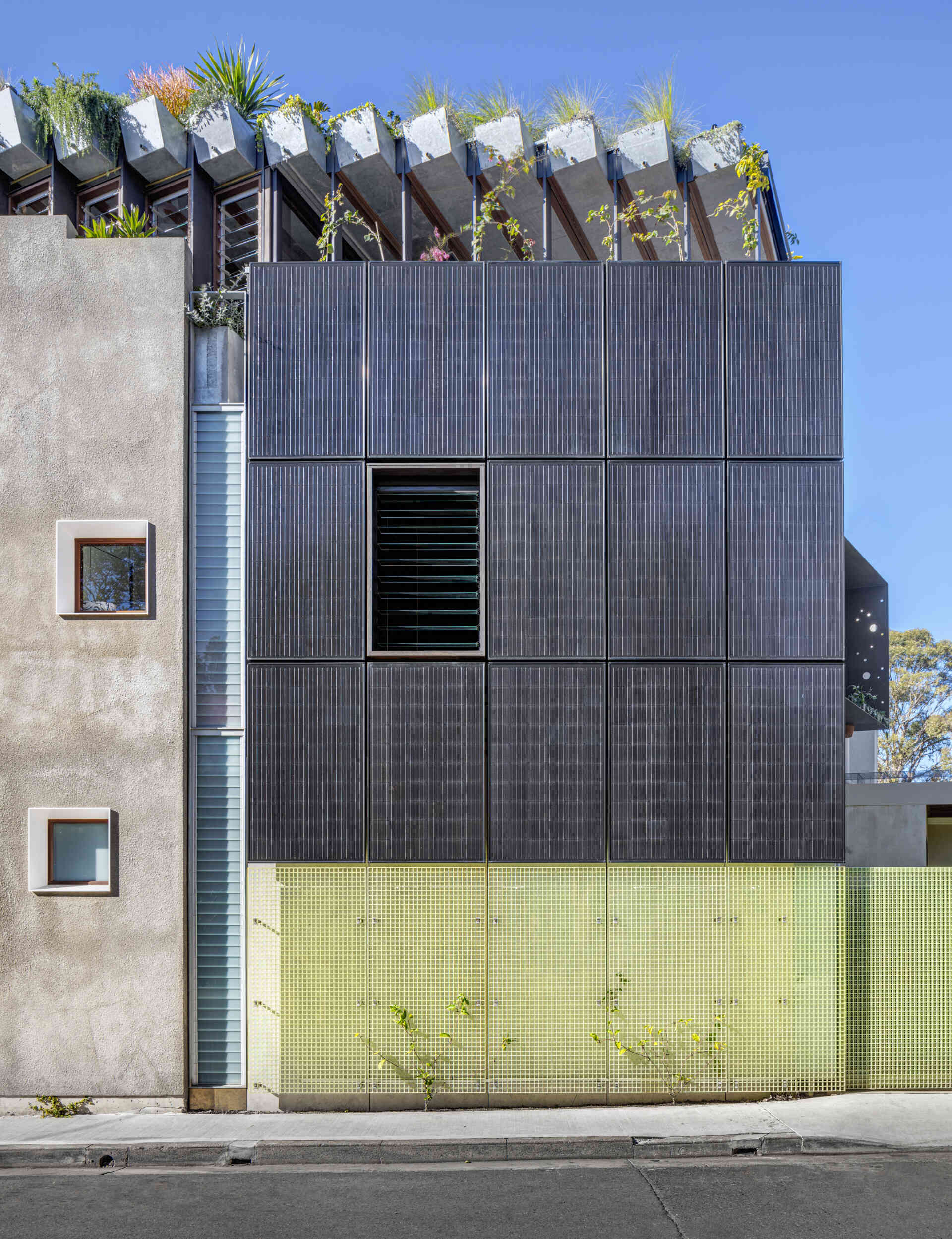 A black photovoltaic panel array punctuates the new northern facade, clearly signaling the home’s commitment to sustainability. These solar panels harness sunlight throughout the day, generating renewable energy to power the household.