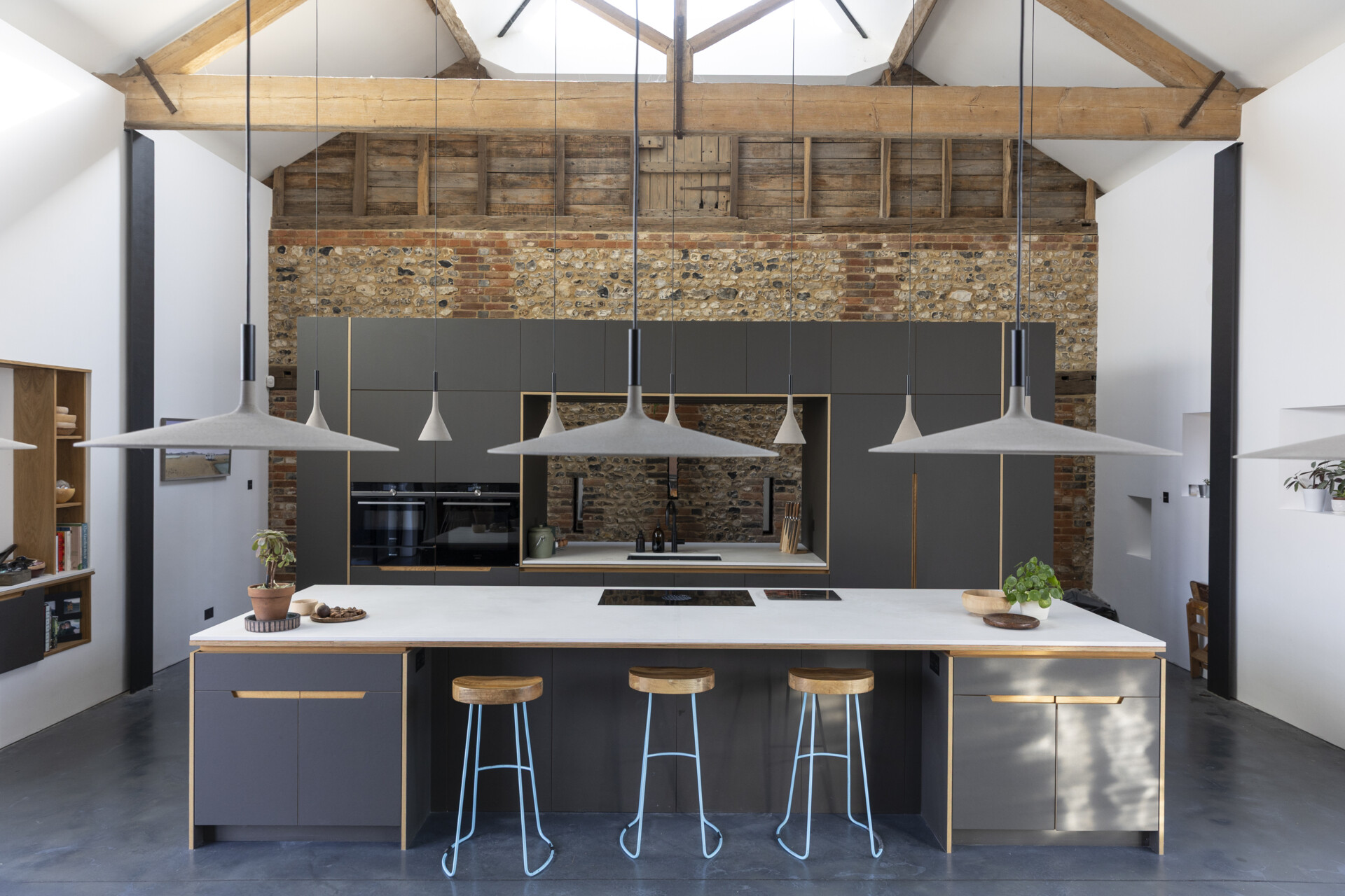 Polished concrete floors and industrial fittings provide a crisp backdrop for this dining area and kitchen that are softened by warm wood accents and custom furnishings.